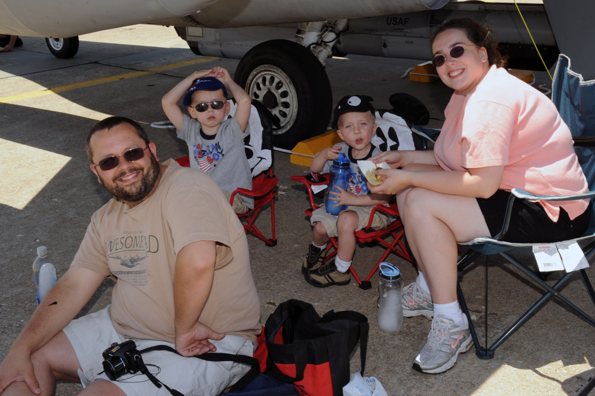 WARRENSBURG, Mo. - The Harrison family of Knob Noster, Mo., rest under the wing of an F-15 during the Wings Over Whiteman Air Show and Open House June 6.  Other aircraft on display include; A-10, civilian planes from the University of Central Missouri and Kansas State University, F-22, and an Apache helicopter. (U.S Air Force photo/Senior Airman Jason Huddleston)