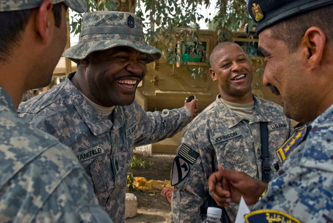 U.S. Army 1st Sgt. Jamie Crankfield, Sgt. 1st Class Anthony Johnson, an interpreter, far left, and a member of the Iraqi national police enjoy a light joke on a break from their briefing on an air upcoming assault mission, June 5, 2009.