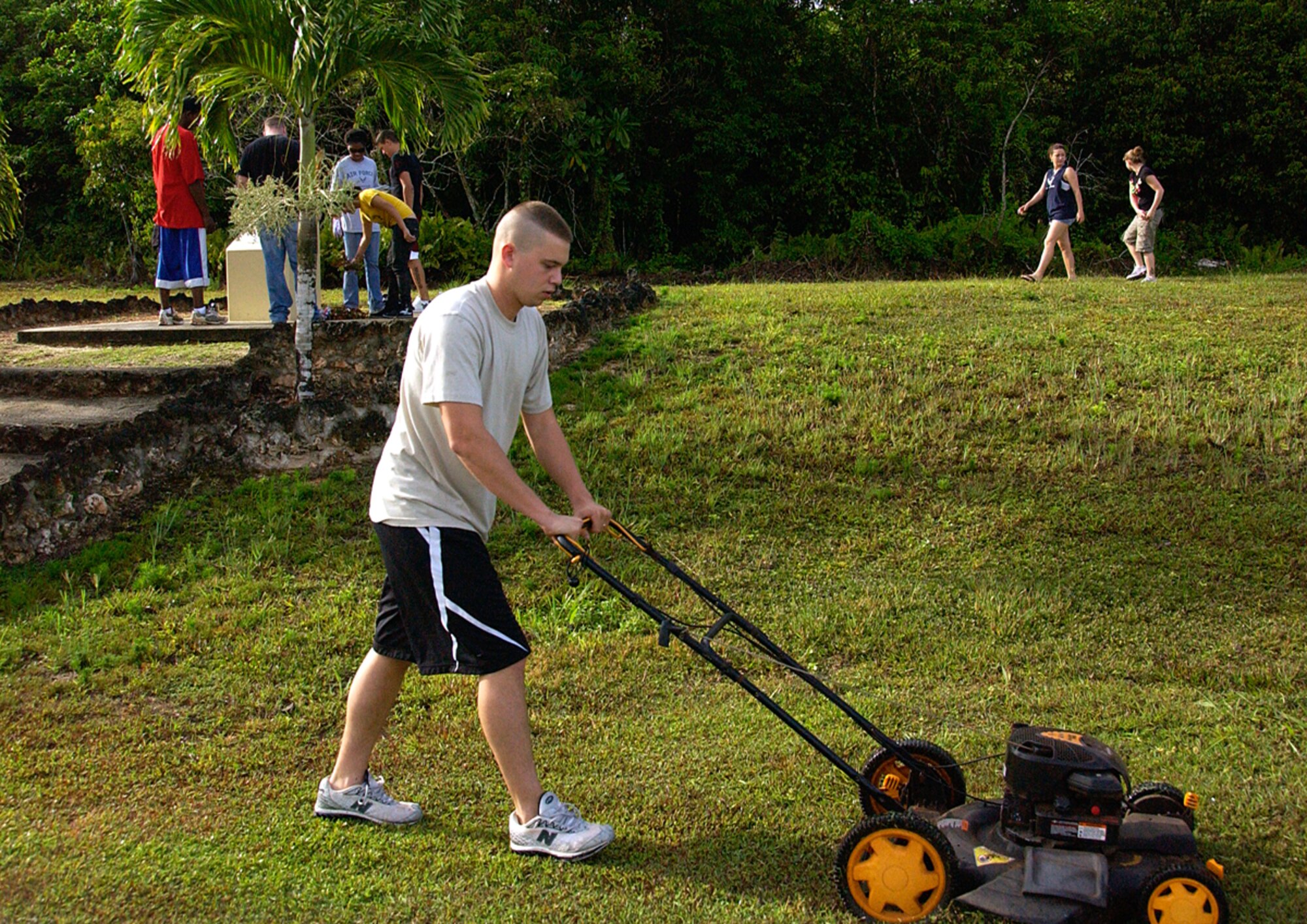 ANDERSEN AIR FORCE BASE, Guam -- Airman 1st Class Ryan Perkins, 36th Communications Squadron communications focal point controller and trustee of Andersen First Four Council, mows grass surrounding the World War II Memorial sponsored by Air Force Sergeants' Association Chapter 1560 June 6. The 10 volunteers from the Andersen First Four Council also swept debris off of the monument and picked up surrounding debris, ensuring the memorial was in pristine condition. Currently, the council performs one volunteer effort each month. (U.S. Air Force photo by Airman Carissa Wolff)     