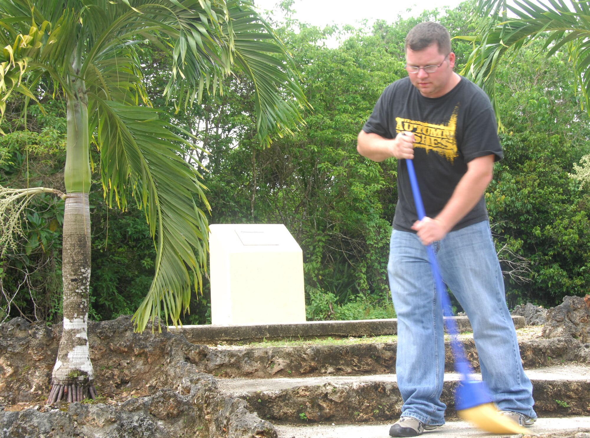 ANDERSEN AIR FORCE BASE, Guam - Senior Airman Shane Dunaway, 36th Wing Public Affairs editor and First Four Council president, sweeps debris from the steps of the Air Force Sergeants Association Chapter 1560-sponsored World War II Memorial June 6. The Andersen First Four Council provides an outlet for Airmen seeking professional growth and strives to be an active part of improving the morale, welfare and quality of life of their peers. (U.S. Air Force photo by Senior Airman Robin Lumm)