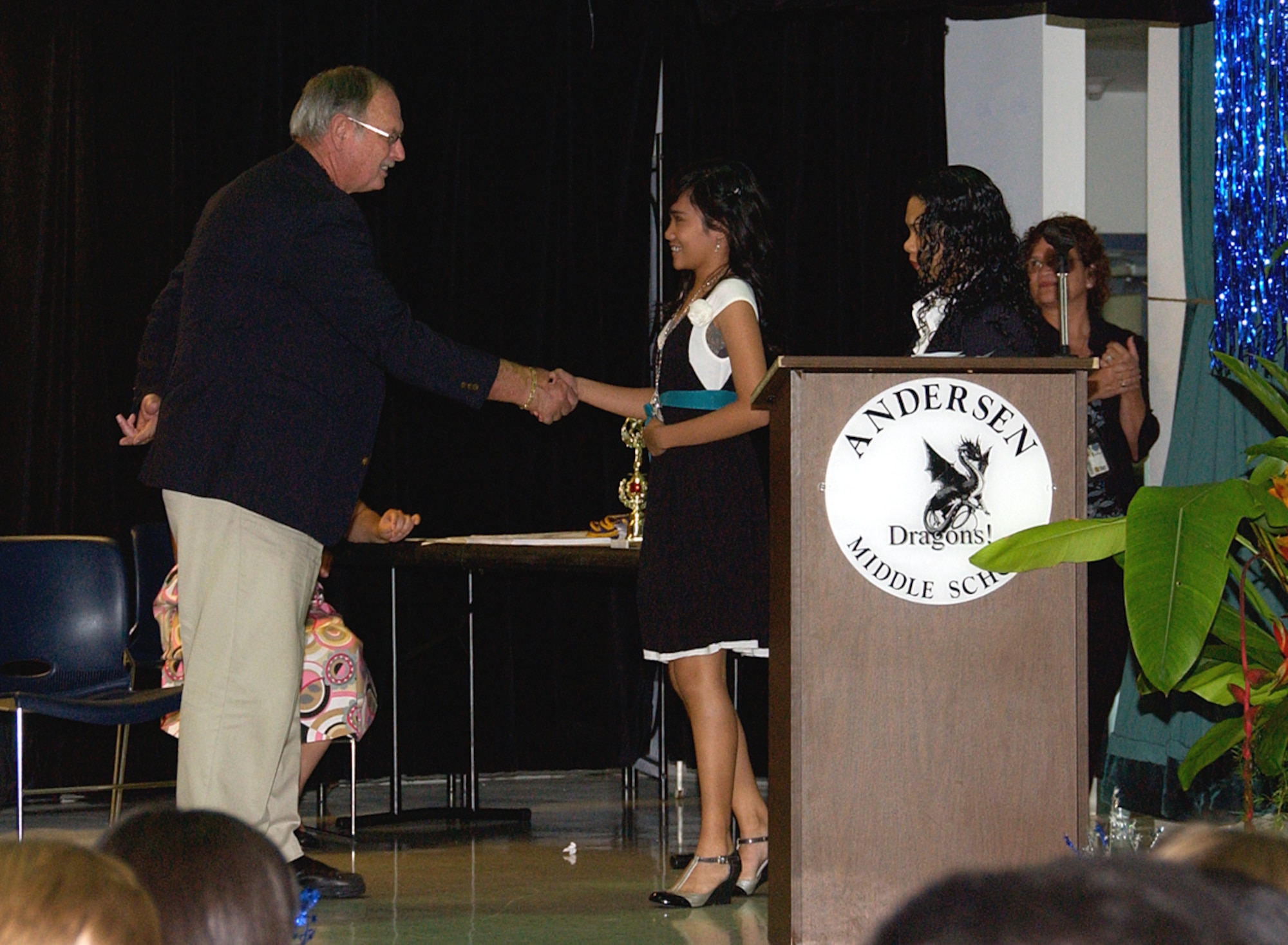 ANDERSEN AIR FORCE BASE, Guam -- Bill Hall, Andersen Middle School principal, shakes hands with Jhenirose Santos, eighth grade President’s Award for Educational Achievement recipient, June 11 at the eighth grade promotion ceremony held in the Dragon Theater. Mr. Hall oversaw the education of 350 students on a yearly basis at AMS by managing all school operations including fulfilling financial, planning and disciplinary roles. He has been the principal of the school for 12 years affecting approximately 4,000 young lives in that time. (U.S. Air Force photo by Airman Carissa Wolff)