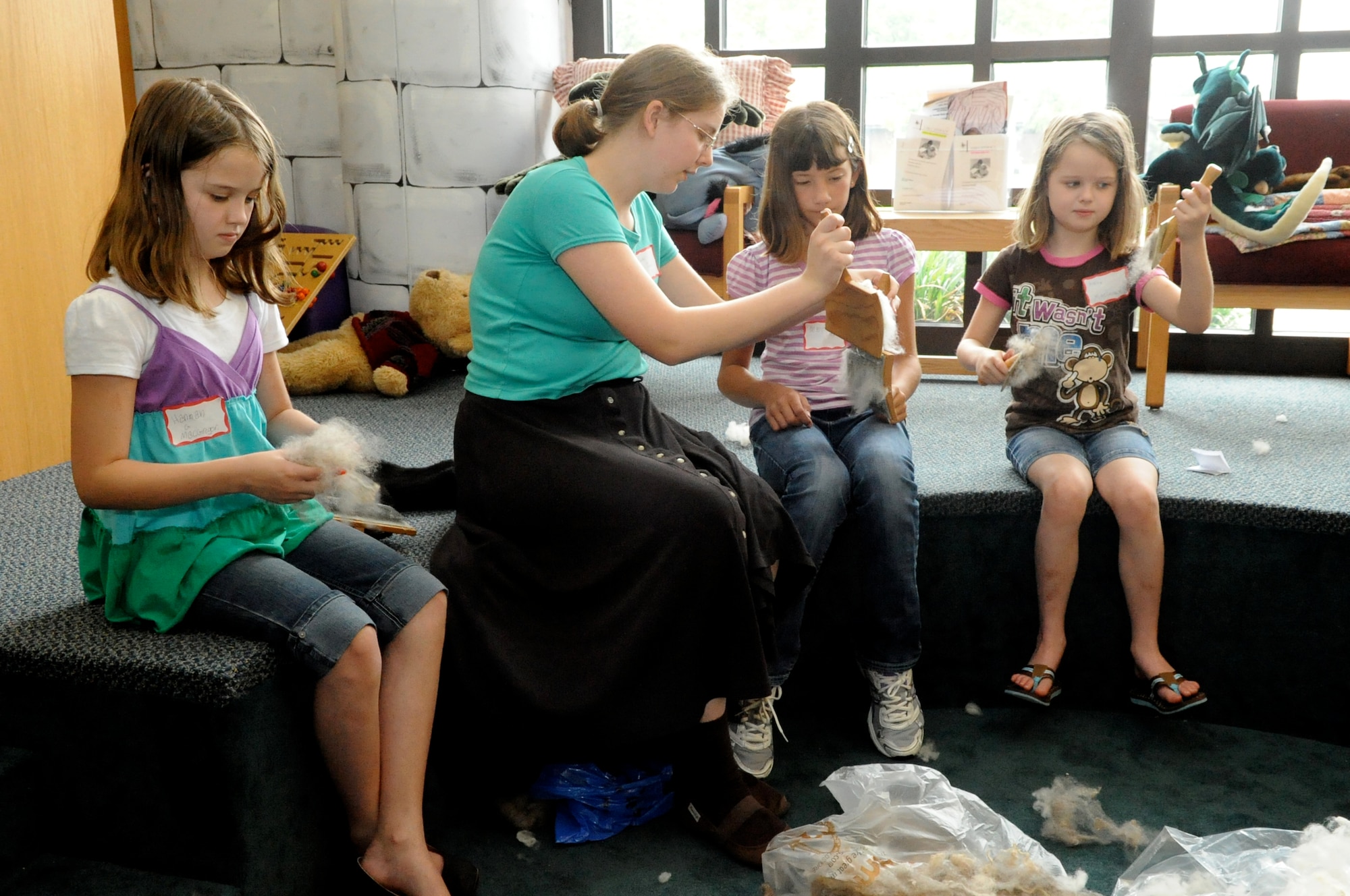 Rachel Johns, second from left, of the South Jersey Guild of Spinners and Hand Weavers, demonstrates a technique called “Carding,” which uses paddle-like brushes, Hand Carders, to straighten out the wool in preparation for the spinning wheel. (U.S. Air Force photo/Wayne Russell)