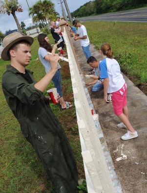 AGANA, Guam – Airmen and Junior Girl Scouts paint a fence at Machananao Elementary School as part of a community service project June 6. More than 100 Airmen from Andersen Air Force Base, Guam, assisted the girls in scrapping rust and painting the fence. (U.S. Air Force photo by Staff Sgt. Jennifer Redente)