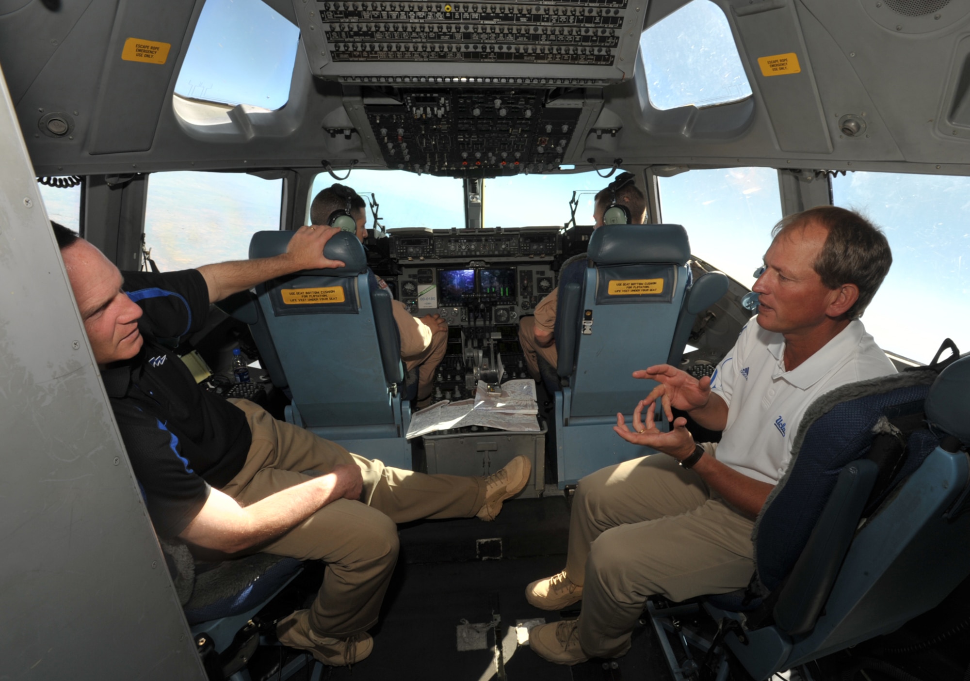UCLA football coach Rick Neuheisel (on right) and Air Force football coach Troy Calhoun talk while riding inside the cockpit of an Air Force C-17 Globemaster headed to Iraq. The flight was part of Coaches Tour 2009, a morale-boosting mission that brought NCAA football coaches to U.S. servicemembers overseas. (U.S. Air Force photo/Tech. Sgt. Jason Schaap)