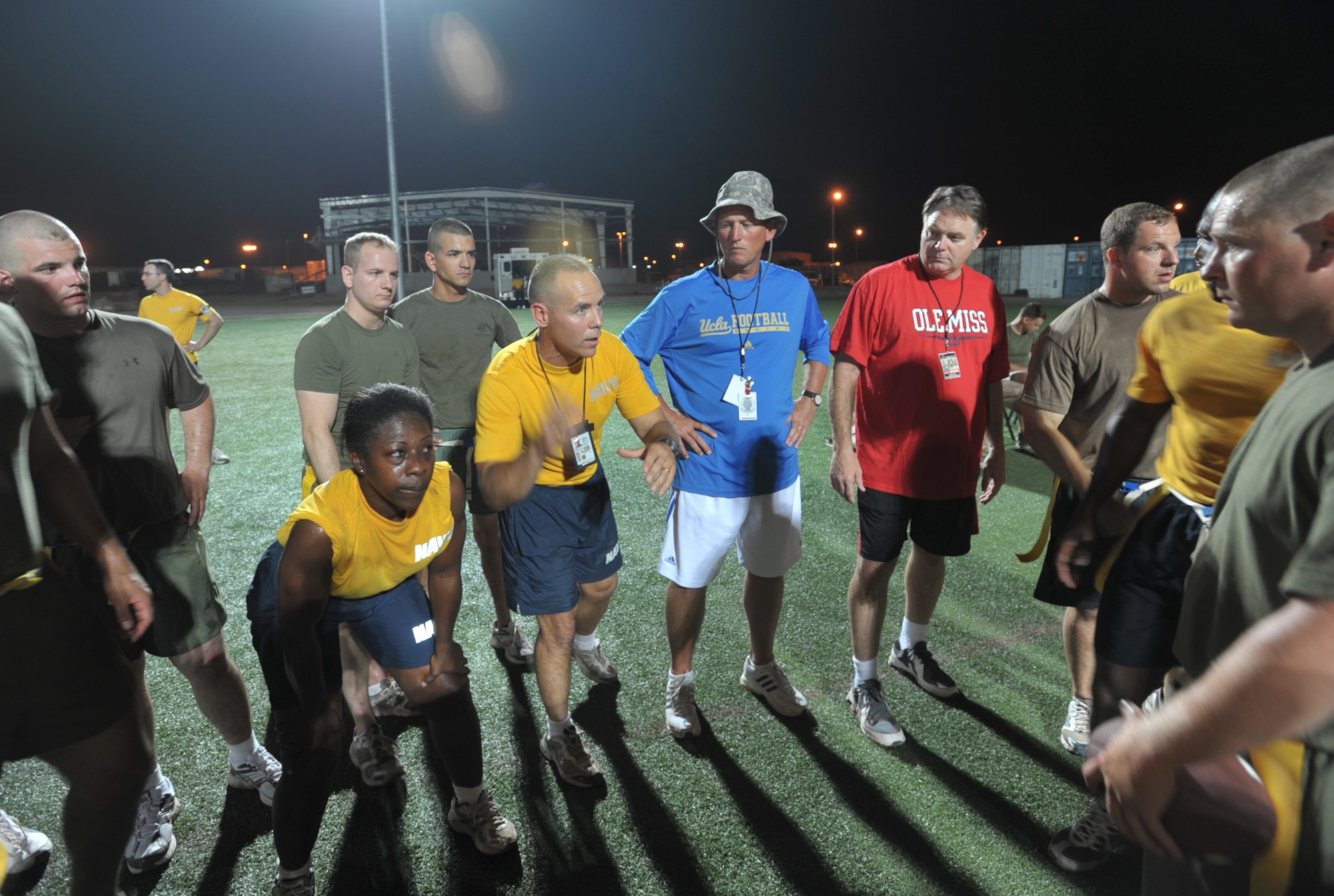 NCAA football coaches Rick Neuheisel of UCLA and Houston Nutt of Ole Miss listen in on a huddle during an Air Force/Army vs. Marines/Navy football game at Camp Lemonier in Djibouti, Africa on June 2. The visit to the camp was part of Coaches Tour 2009, a morale-boosting mission that brought seven NCAA coaches to U.S. servicemembers. (U.S. Air Force photo/Tech. Sgt. Jason Schaap)