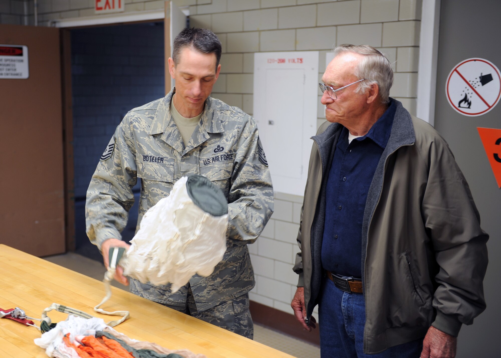 MINOT AIR FORCE BASE, ND -- Senior Master Sgt. Kenneth Boteler, 5th Operational Support Squadron’s Air Flight Crew Equipment superintendent, explains to Mr. Harold Uhlich of Garrison, N.D. how a modern parachute is deployed, here June 11. Mr. Uhlich acquired the piece while serving in a security detail in Sasebo, Japan for the U.S. Marine Corps from 1944 to 1946. (US Air Force photo by Staff Sgt. Keith Ballard)