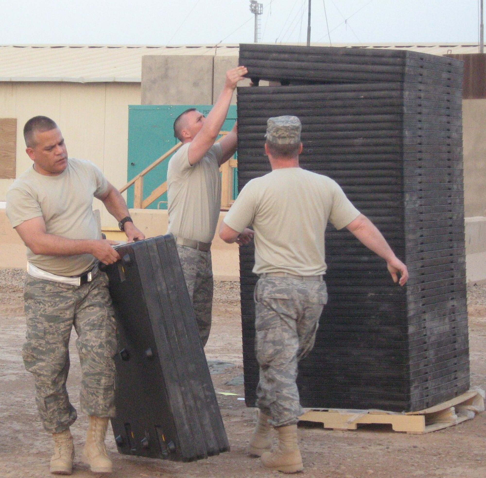 WRIGHT-PATTERSON AIR FORCE BASE, Ohio – Maj. John Marang, 87th Aerial Port Squadron, currently deployed with the 332nd Expeditionary Logistics Readiness Squadron, works with Master Sgt. Bruce Kastner and Master Sgt. David Vanwinkle, also from the 332nd ELRS, to move tri-walls into a container unit at the temporary storage yard. Their goal is to recover 40% of the containers on Joint Base Balad to be placed back into the transportation system for movement. (Courtesy photo)