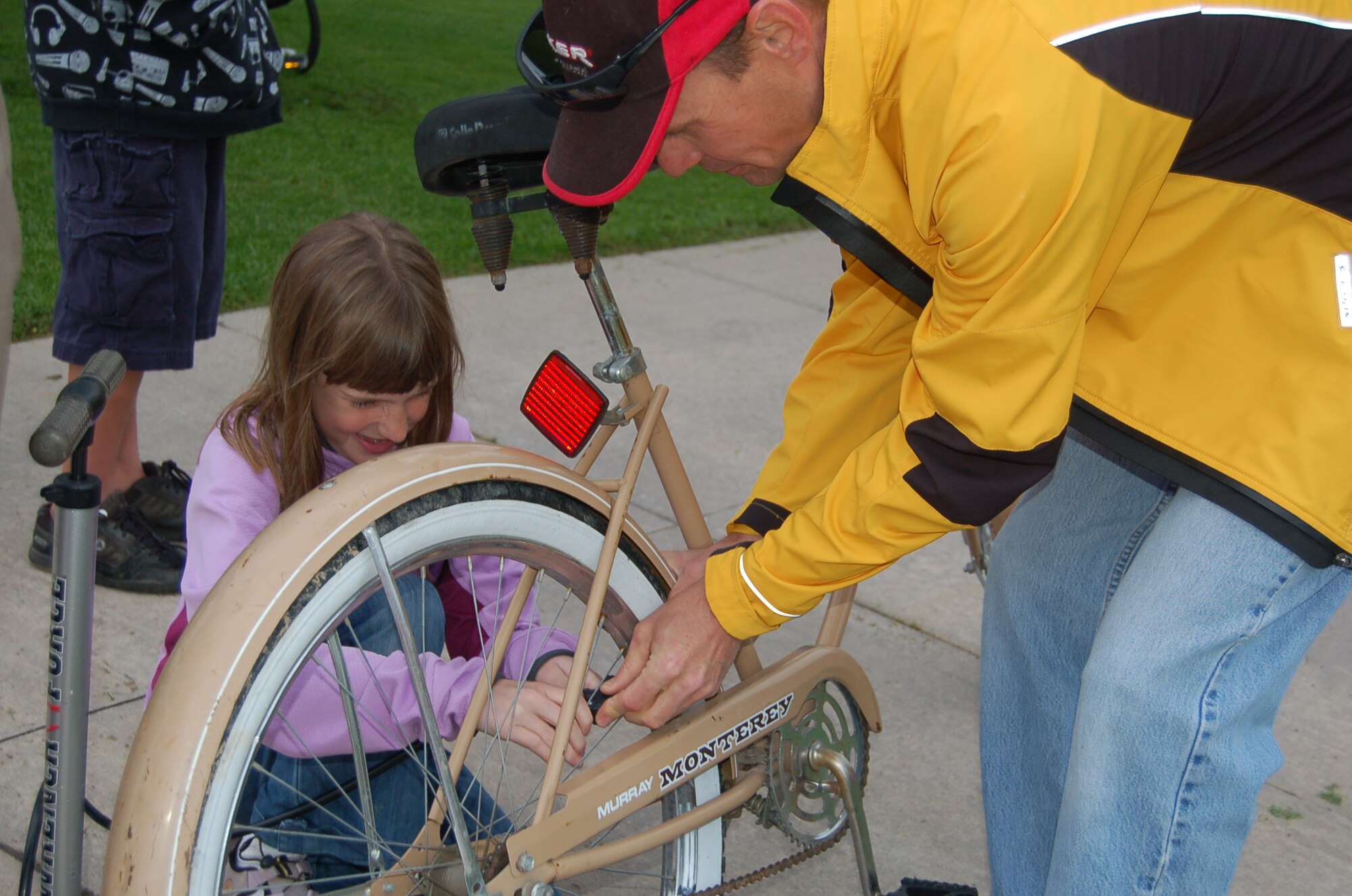Nine-year-old Katherine Lawrence and Eldon Goates, Front Rangers mountain bike coach, check the tire pressure of a beach cruiser during the Bike to Work day Amazing Base Race and scavenger hunt here June 10. Ms. Lawrence is a member of Front Rangers, a USA Cycling sanctioned youth cycling club that assisted race participants. About 300 competitive youth cyclists are between here and Denver, said Ed Browne, Air Force Space Command safety office and Front Rangers club president. (U.S. Air Force photo by Thea Skinner)
