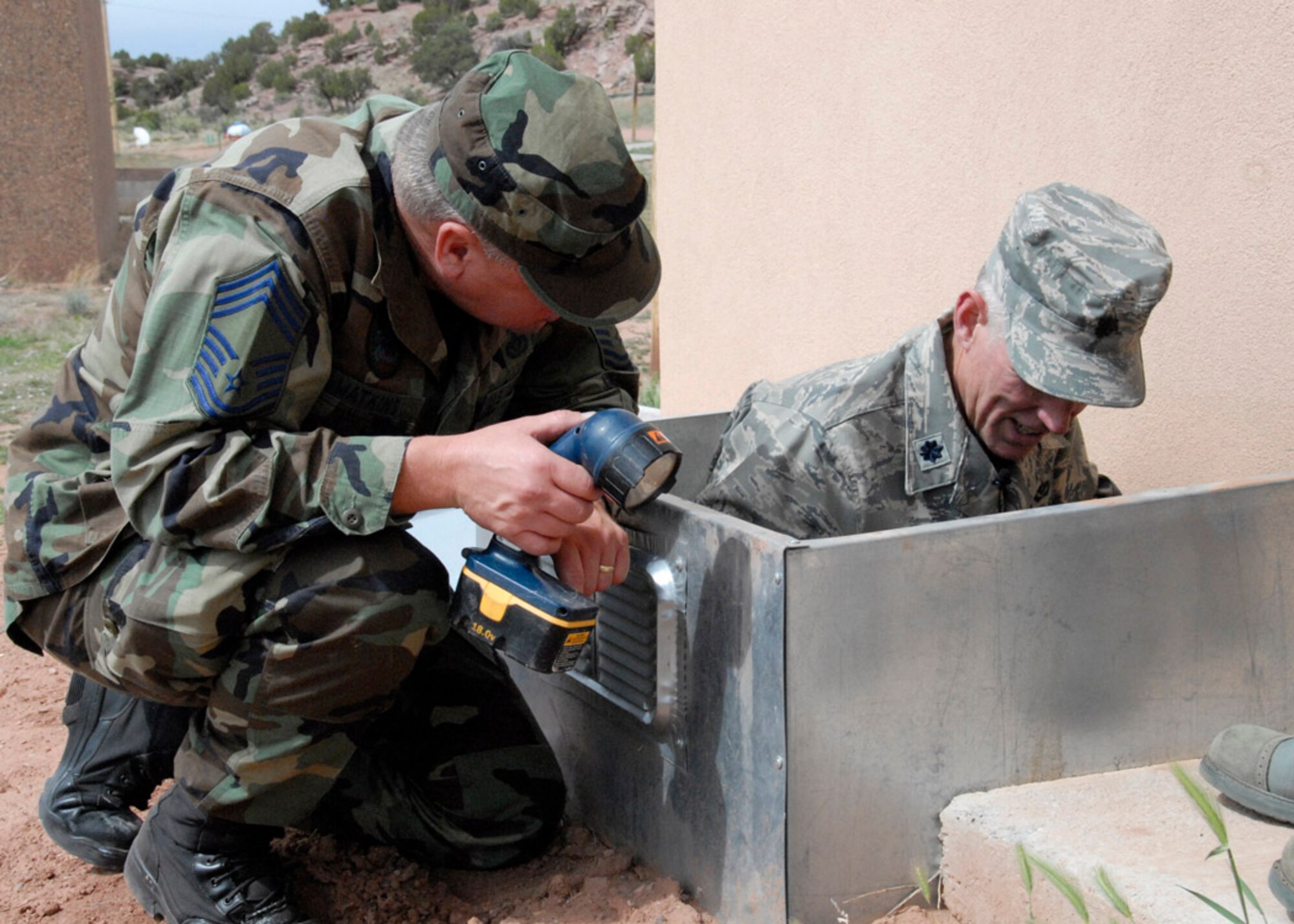 Chief Master Sgt. Leslie Watkins and Lt. Col. Thomas Niichel, 240th Civil Engineer Squadron, examine damage caused by the rain and mud on a newly-built dining hall at Saint Michael?s Association for Special Education June 8, 2009 near Window Rock, Az.. 