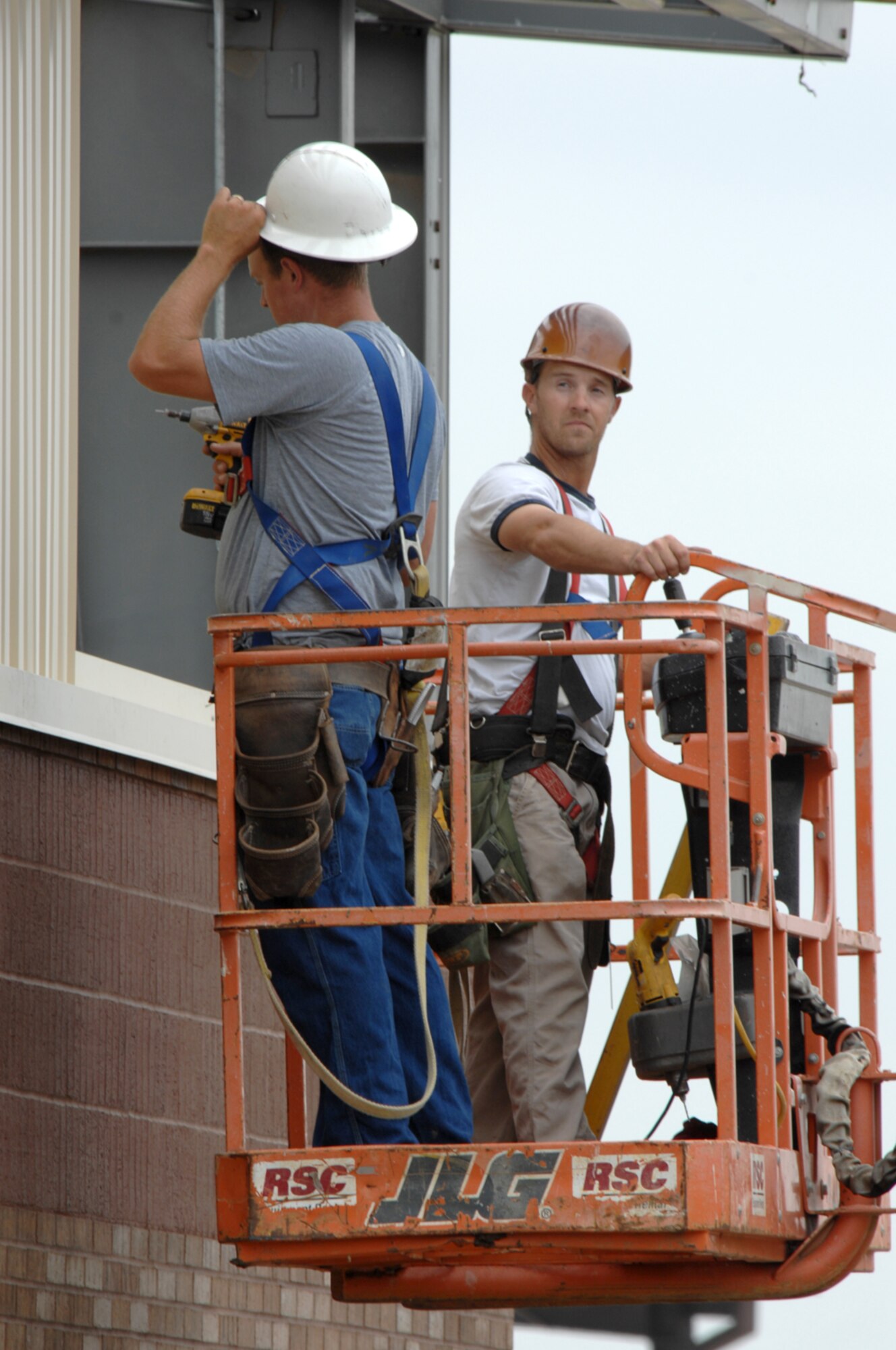 WHITEMAN AIR FORCE BASE, Mo. - Cliff Bayless (Right) and Matt Shackelford (Left), contractors with Larry Brandt Construction, operate a man lift to reposition themselves while installing sheet metal siding June 10. The workers are constructing an addition to the 442nd Fighter Wing munitions maintenance facility. (U.S. Air Force photo/Tech. Sgt. Charles Larkin)