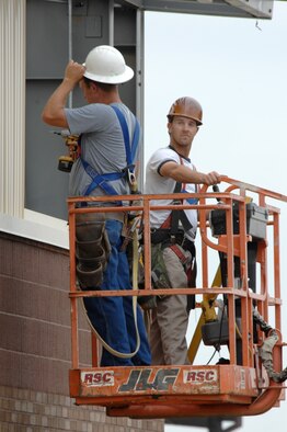 WHITEMAN AIR FORCE BASE, Mo. - Cliff Bayless (Right) and Matt Shackelford (Left), contractors with Larry Brandt Construction, operate a man lift to reposition themselves while installing sheet metal siding June 10. The workers are constructing an addition to the 442nd Fighter Wing munitions maintenance facility. (U.S. Air Force photo/Tech. Sgt. Charles Larkin)