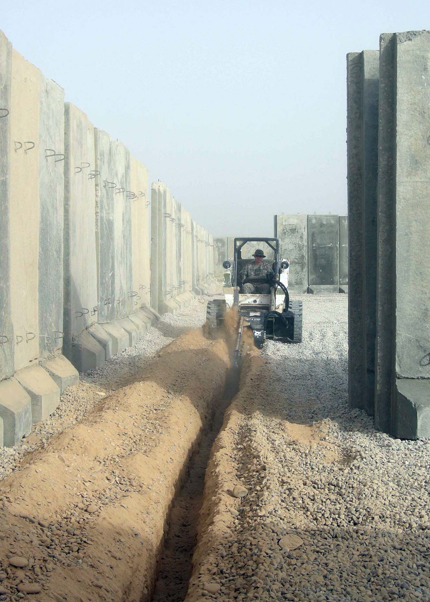 Staff Sgt. Justin Degarmo, 732nd Expeditionary Civil Engineer Squadron Detachment 3, operates a bobcat with a trenching attachment as he buried electrical cables at Patrol Base Shocker, Iraq in April 2009. More than 6,000 feet of cable was placed to support the requirements for more than 20 newly constructed facilities. Over 15 tents, shower/shave units and guard towers were among the facilities added to the electrical grid. Sergeant Degarmo was part of the construction team that supported the vertical construction phase, which doubled the size of the installation to bed-down over 140 additional US Soldiers to be assigned to Patrol Base Shocker. Sergeant Degarmo is deployed from Fairchild Air Force Base, Wash. and a native of Spokane, Wash. (Courtesy Photo)