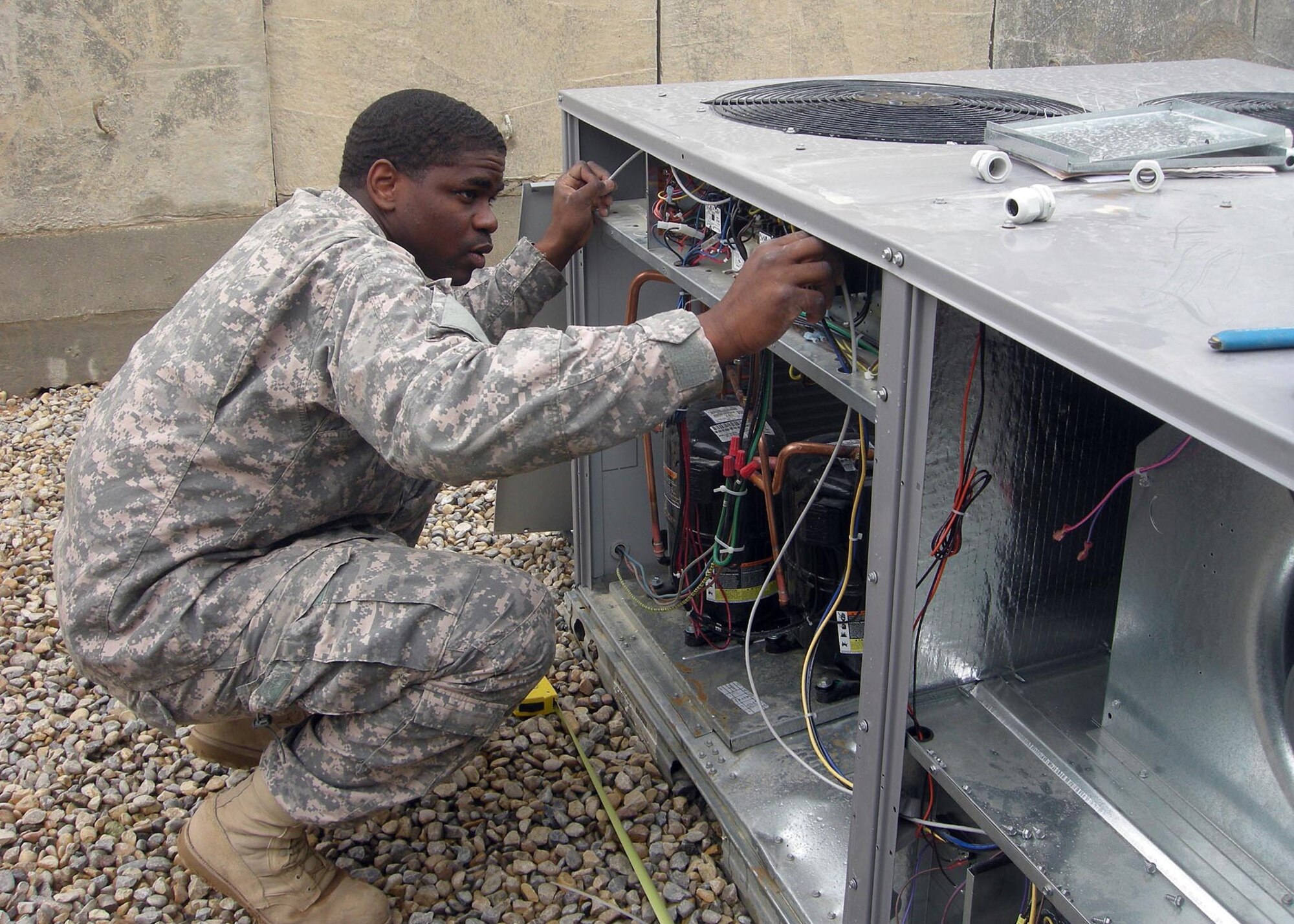 Senior Airman Tyrese Buie, 732nd Expeditionary Civil Engineer Squadron Detachment 3, troubleshoots a malfunctioning air conditioning unit at Patrol Base Shocker, Iraq in May 2009.  Airman Buie is part of a multi-craft team with over 15 members, which supported the vertical construction phase to bed-down over 140 additional Soldiers assigned to Patrol Base Shocker.  Airman Buie is deployed from F.E Warren Air Force Base, Wyo., and a native of Savannah, Ga.  (Courtesy Photo)
