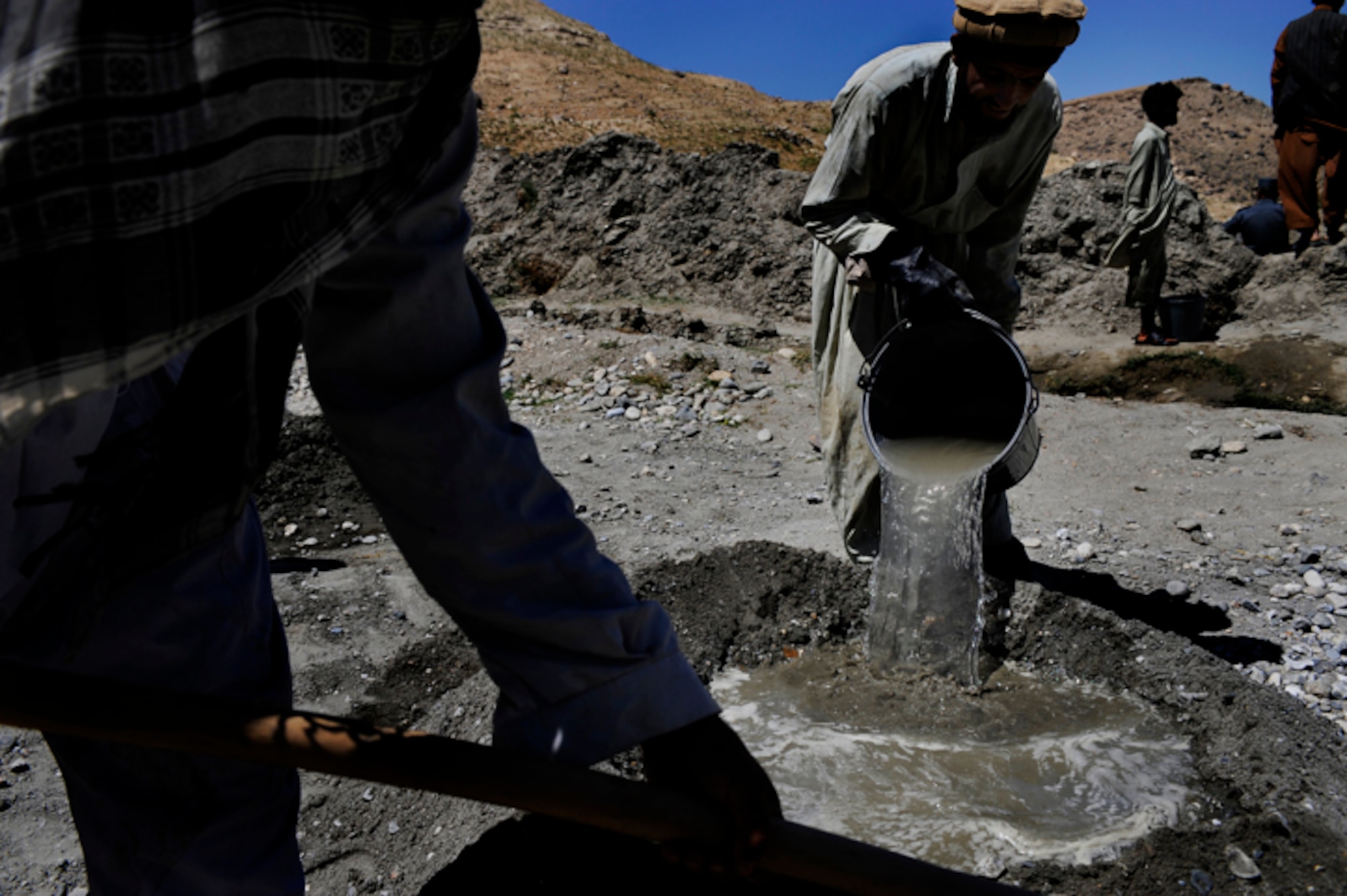 Contract workers in the Rodat community mix together concrete to seal the walls of a well May 28. The project is developed and monitored by the Nangarhar Agri-Business Development Team, Forward Operating Base Finley-Sheilds, which is responsible for designing projects which will improve the agricultural production of rural farming communities in the province. The team supports the construction of wells, karizes, veterinary clinics, reforestation projects to name a few.