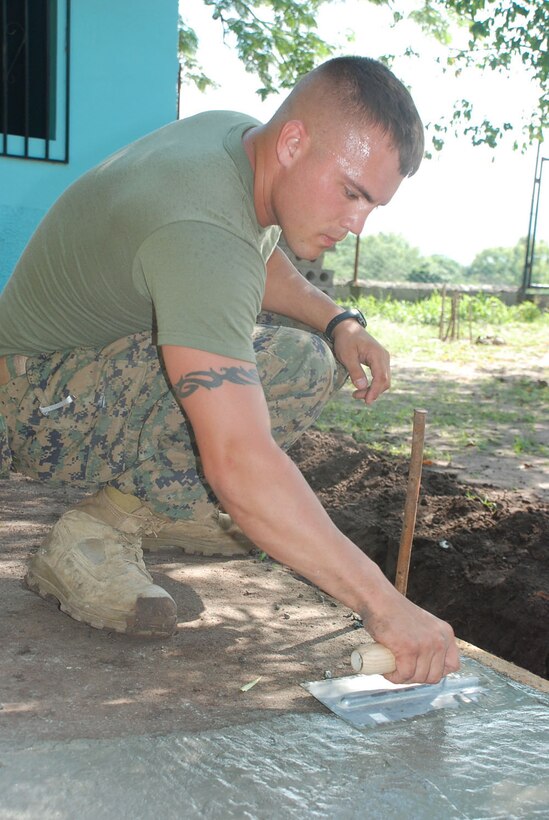 MIRA VALLE LA PAZ, Honduras - U.S. Marine Corps Lance Cpl. Casey Ruff puts the finishing touches on a sidewalk after running a water line to a school here from a water tower across the street.  The lance corporal is assigned to Alpha Company, 4th Combat Engineering Battalion in Crosslands, W.V.  He is here for three weeks with Beyond the Horizon, a large-scale exercise completing medical readiness missions and civil engineer projects throughout Central America.  (U.S. Air Force photo/ Tech. Sgt. Rebecca Danét)