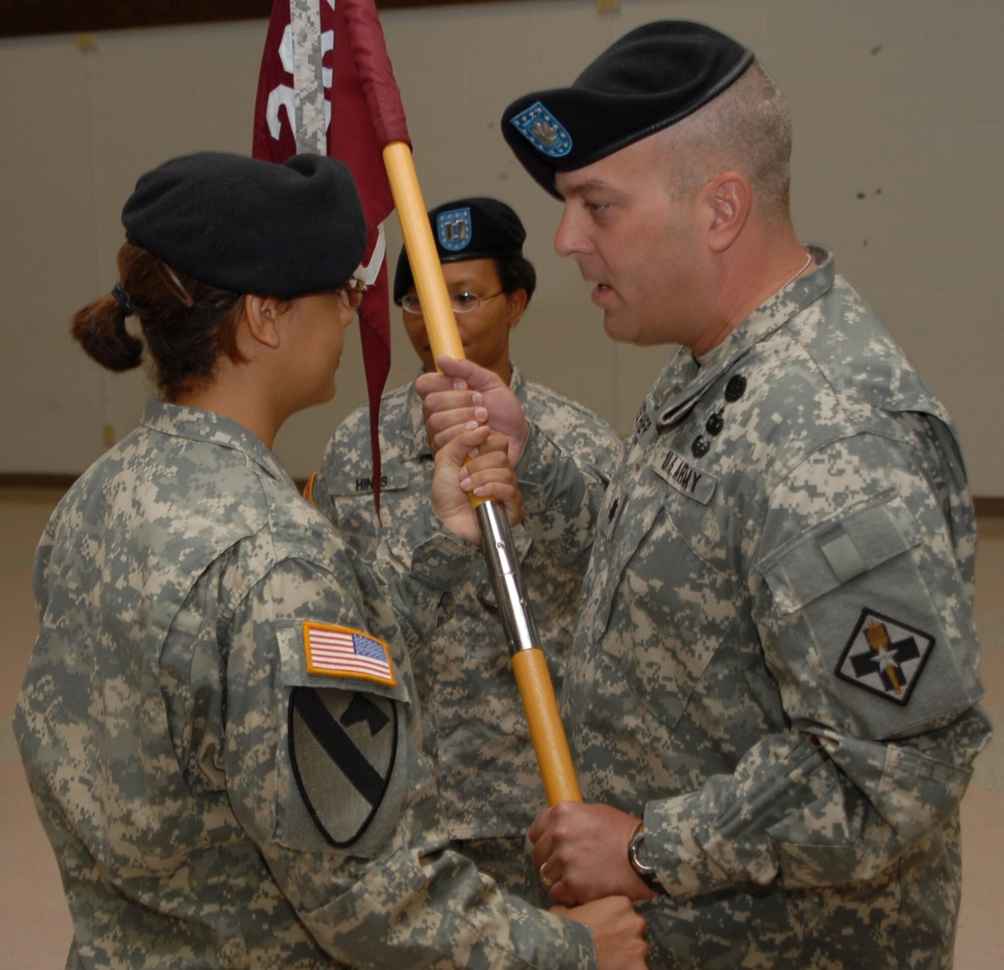 Lt. Col. Scott Fischer, right, passes the D-Company 264th Medical Battalion guidon to Capt. Dominique Henry June 16 during an assumption of command ceremony. Capt. Henry replaced Capt. Danielle Hines. (U.S. Air Force photo/ Lou Anne Sledge)