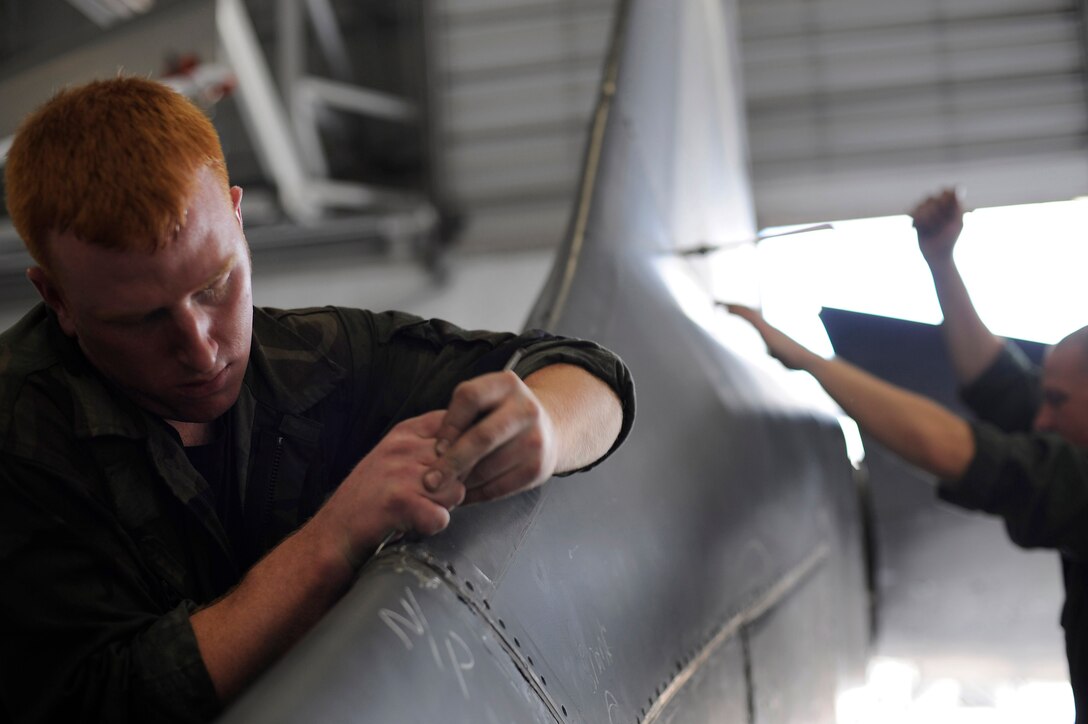(Front) Senior Airman Eric Smith, 28th Aircraft Maintenance Squadron isochronal inspection technician, and Staff Sgt. Joseph Canet, 28th Aircraft Maintenance Squadron crew chief, removes the saddle paddle of a B-1B Lancer here, June 16. The average time to complete an isochronal inspection on a B-1B Lancer is 15 days.  (U.S. Air Force photo by Airman 1st Class Corey Hook)