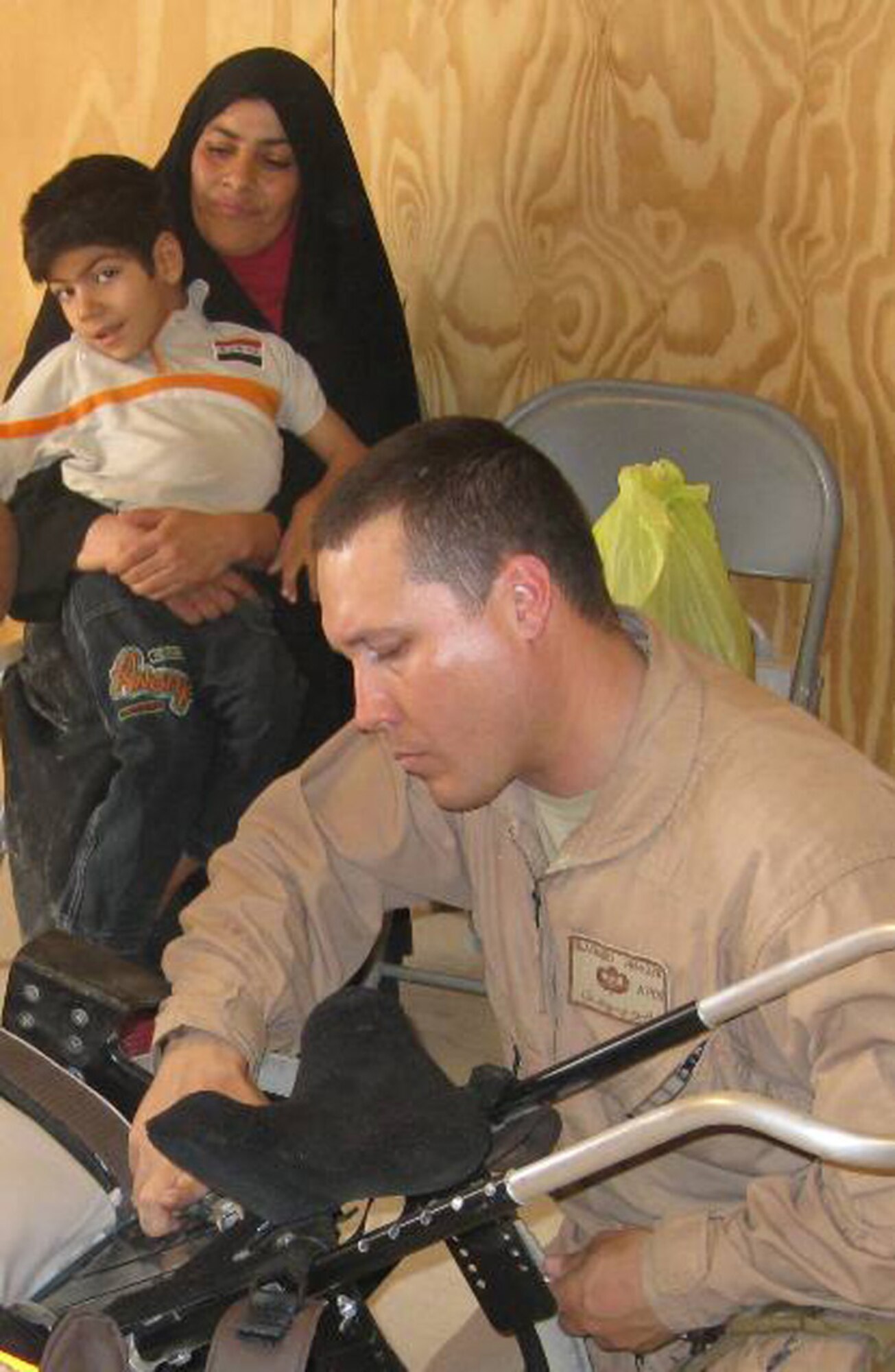 In this undated photo, an Airman helps custom fit a pediatric wheelchair for an Iraqi child. A C-130 aircrew from the Air Force Reserve's 302nd Airlift Wing, Peterson Air Force Base, Colo., flew wheelchairs like this one to Andrews AFB, Md., where another plane took the wheelchairs to Baghdad, Iraq. (Courtesy photo/Brad Blasuer)