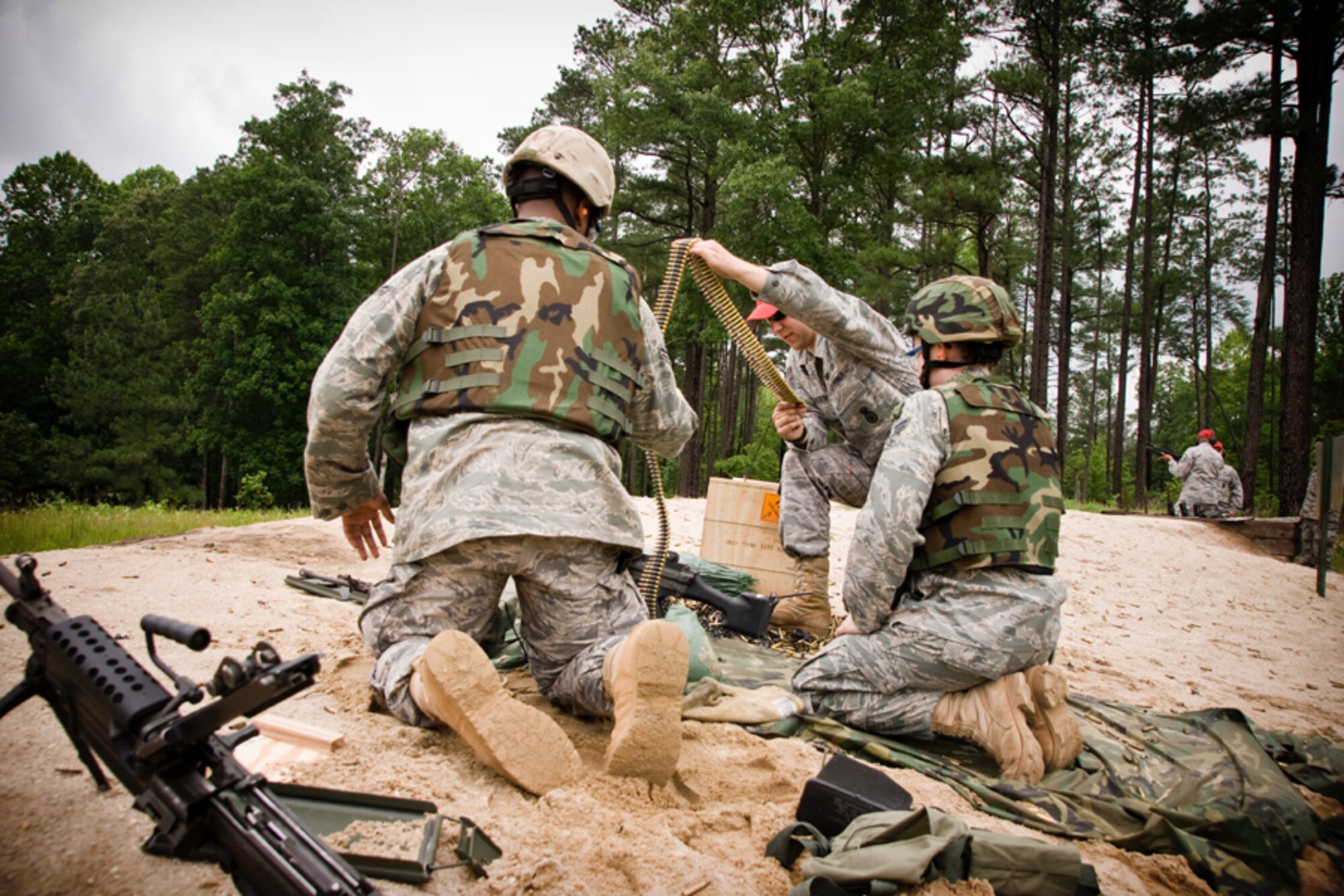 Senior Airman Ryan Matheson prepares a long strand of 5.56mm ammunition for Airman First Class Franklin Hawkins and Airman Ame Perez at a M249 firing position. (U.S. Air Force Photo/ Capt. Nick Strocchia)
