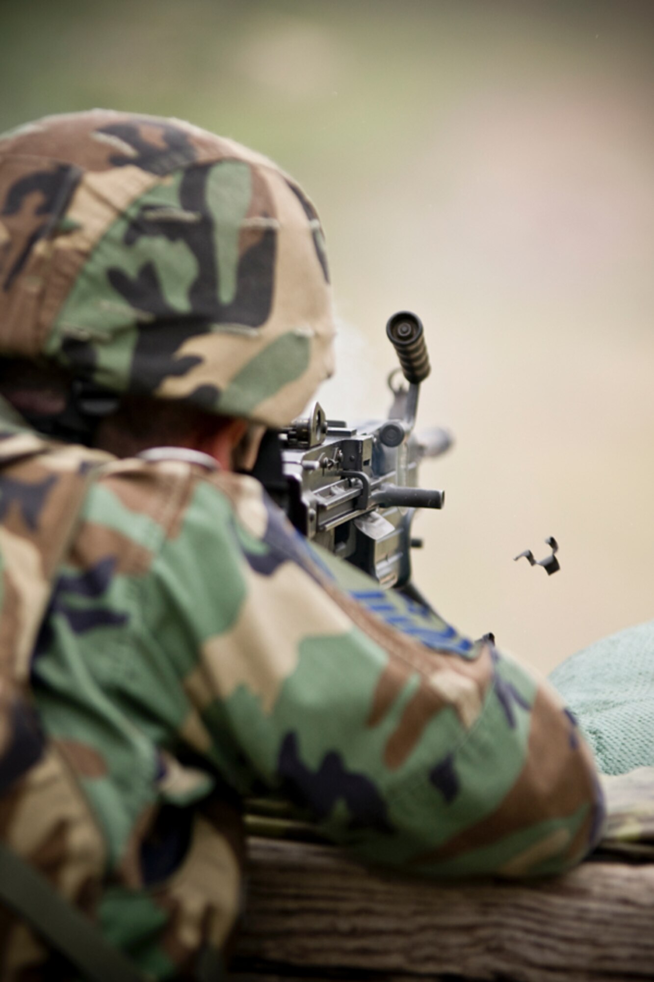 Senior Master Sgt. Todd Cory fires off one the first rounds of the day from his M249 bunker firing position.  The rounds from the M249 eject vertically downward, while the ammo links eject horizontally. (U.S. Air Force Photo/ Capt. Nick Strocchia)
