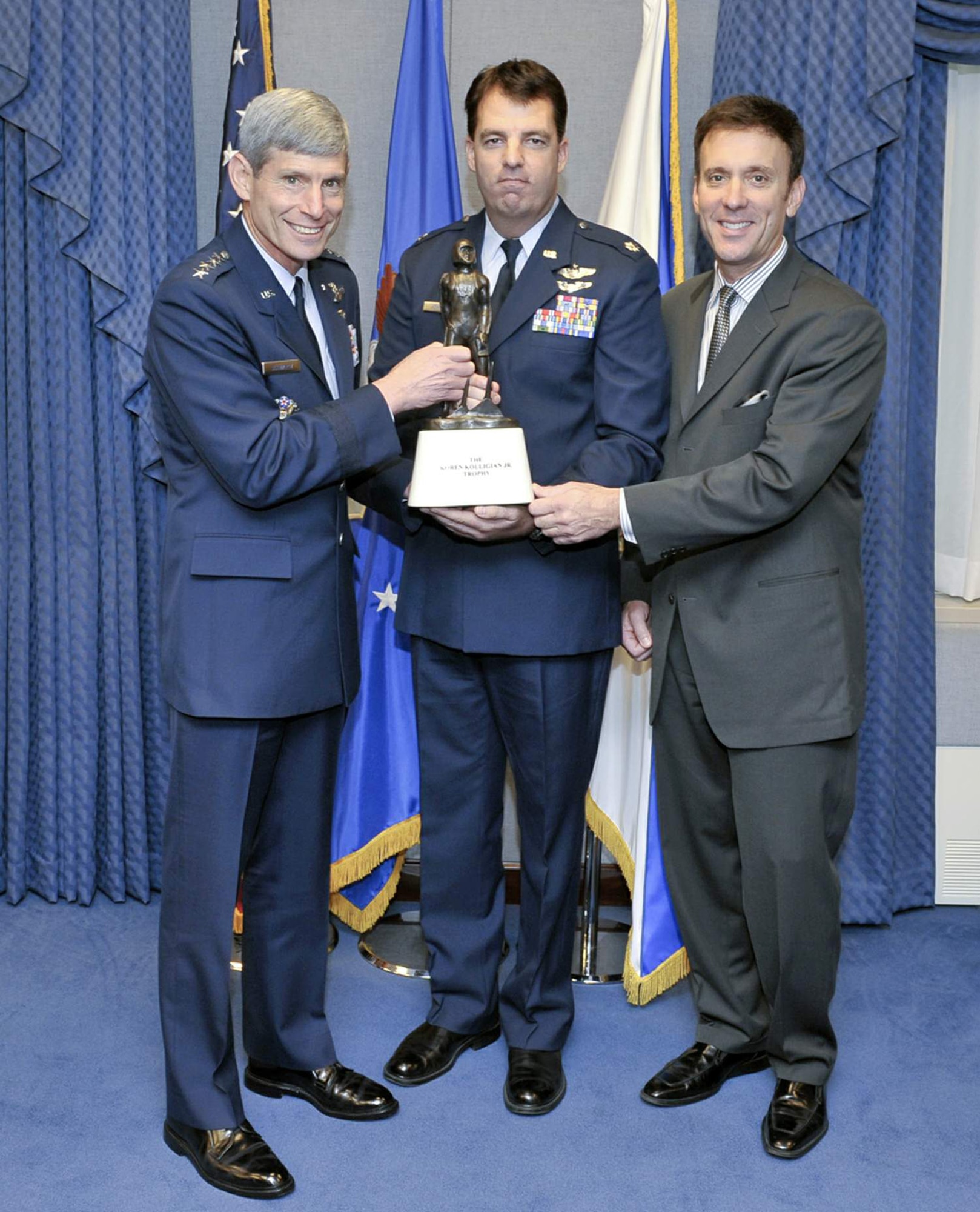 Air Force Chief of Staff Gen. Norton Schwartz assisted by Koren Kolligan presents Lt. Col. Booth M. Johnston with the Koren Kolligian Jr. Safety Trophy June 16. He received the award for an October 2007 incident in which he suffered a severe back and neck injury during a high-G maneuver. Despite the near total loss of use and lack of sensation in his hands and feet, Colonel Johnston was eventually able to level the aircraft and land at Ellington Field, Texas. (U.S. Air Force photo/Michael Pausic) 