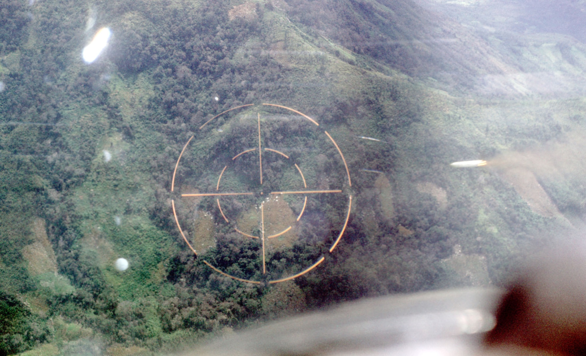 After identifying a target, the FAC called for attack aircraft and marked the target.  Here, an O-2 FAC fires a white phosphorus rocket (just to the right of the gunsight’s crosshairs) near Phan Rang in 1969. (U.S. Air Force photo)