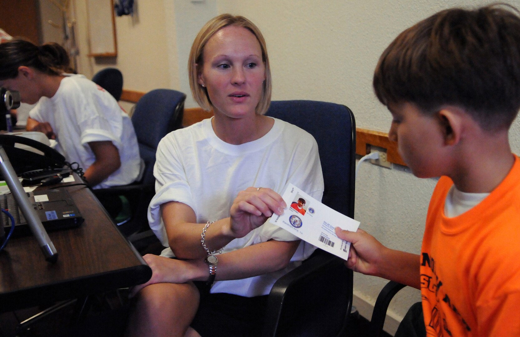 Tech. Sgt. Angela Schlosser, an Airman Leadership School instructor, gives Ethan Beckman his identification card printout during the Airman and Family Readiness Flight's Operation Families Learning About Global Support, or FLAGS, event June 12. Operation FLAGS is a simulated deployment experience for family members to learn what their mom, dad, husband or wife goes through while preparing to deploy. (U.S. Air Force photo by Don Lindsey)