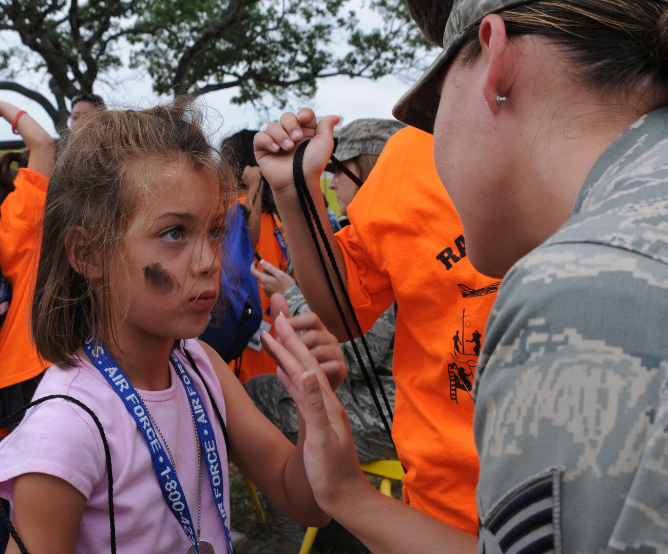 Kali Colo holds still while she's made up with camoflauge paint during the Airman and Family Readiness Flight's Operation Families Learning About Global Support, or FLAGS, event June 12. Operation FLAGS is a simulated deployment experience for family members to learn what their mom, dad, husband or wife goes through while preparing to deploy. (U.S. Air Force photo by Don Lindsey)
