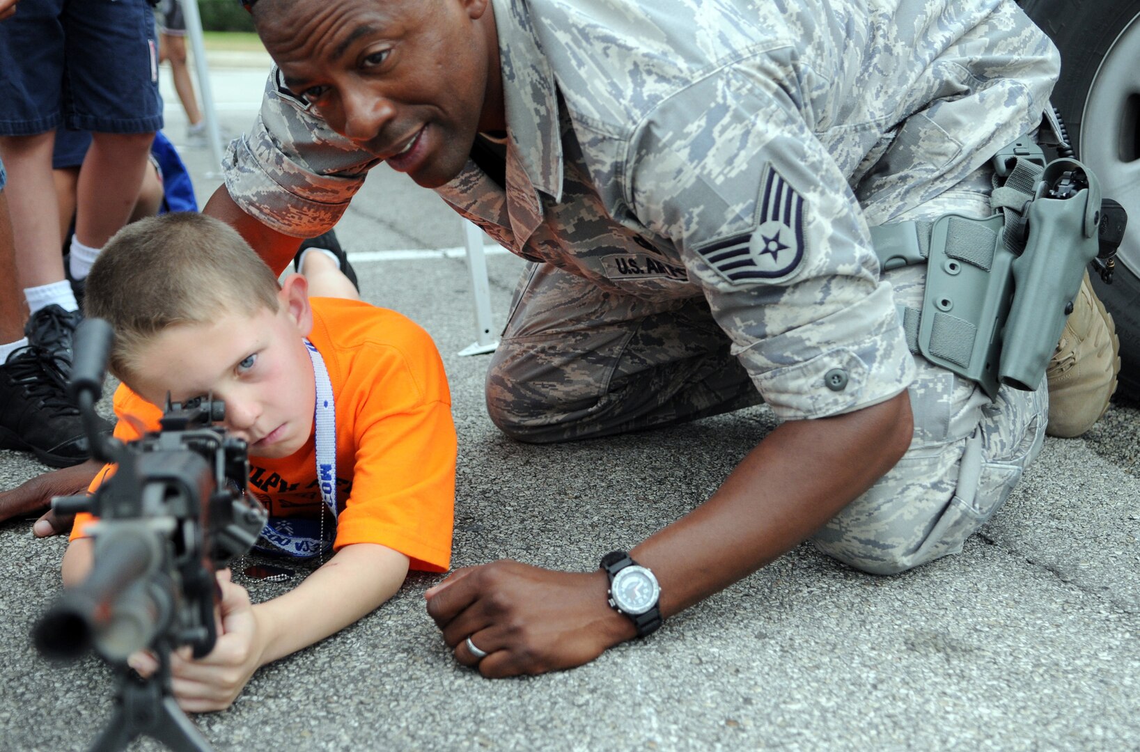 Staff Sgt. William Graham, 12th Security Forces Squadron, helps Hayden Holcomb take aim at a simulated target during the Airman and Family Readiness Flight's Operation Families Learning About Global Support, or FLAGS, event June 12. Operation FLAGS is a simulated deployment experience for family members to learn what their mom, dad, husband or wife goes through while preparing to deploy. (U.S. Air Force photo by Don Lindsey)
