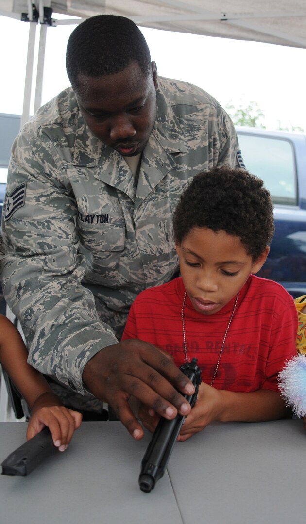 Staff Sgt. Sammy Clayton, 12th Security Forces Squadron, teaches handgun nomenclature to Brenden Boswell during the Airman and Family Readiness Flight's Operation Families Learning About Global Support, or FLAGS, event June 12. Operation FLAGS is a simulated deployment experience for family members to learn what their mom, dad, husband or wife goes through while preparing to deploy. (U.S. Air Force photo by Don Lindsey)