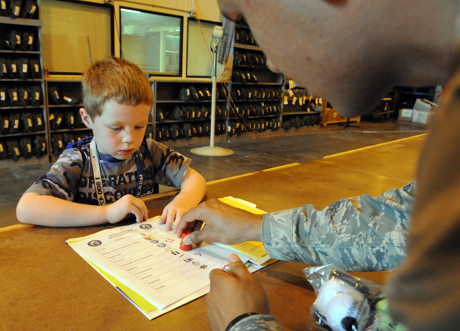 Trevor Jackson waits to have his forms stamped during the Airman and Family Readiness Flight's Operation Families Learning About Global Support, or FLAGS, event June 12. Operation FLAGS is a simulated deployment experience for family members to learn what their mom, dad, husband or wife goes through while preparing to deploy. (U.S. Air Force photo by Don Lindsey)