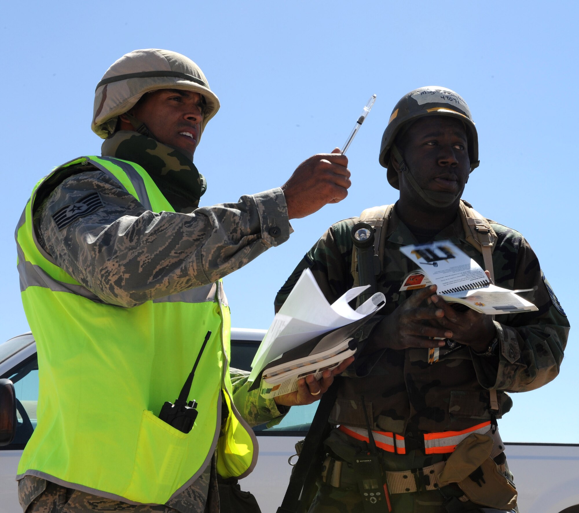 Master Sgt. Jimmy Green, 49th Medical Support Squadron, is evaluated by an Exercise Evaluation Team member after a simulated aircraft attack during the Phase II exercise at Holloman Air Force Base, N.M. After finding a simulated unexploded ordinance, Sergeant Green uses his Airman?s Manual to ensure he follows the correct safety procedures. He later formed a human cordon around the UXO to make certain no one crossed its path. (U.S. Air Force photo/Airman 1st Class Sondra M. Escutia)