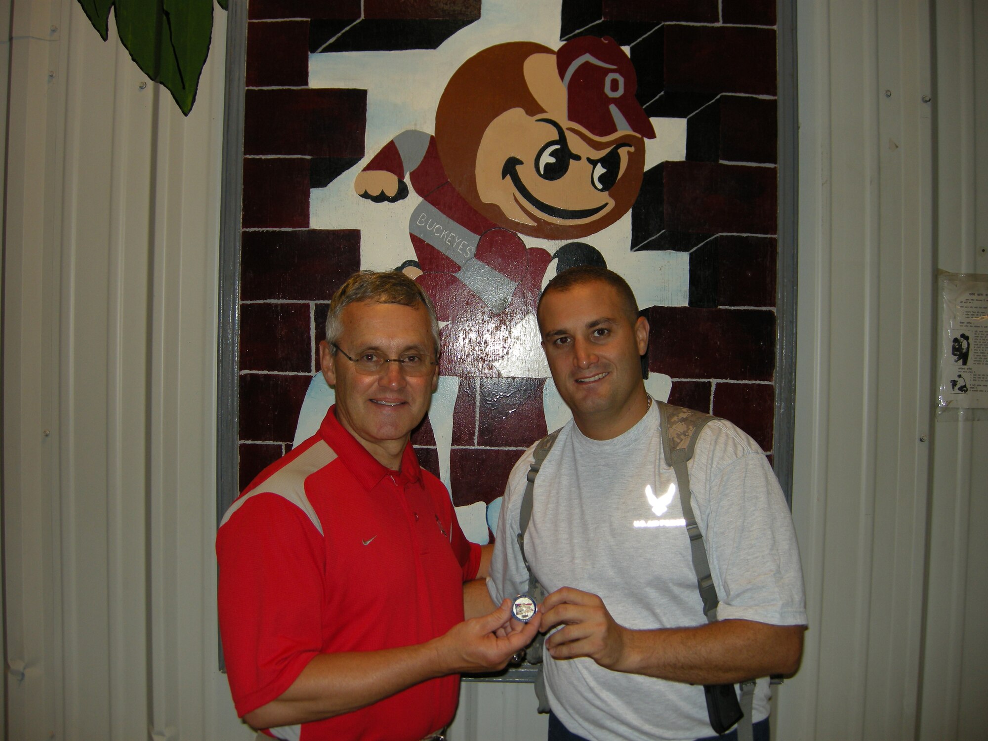 WRIGHT-PATTERSON AIR FORCE BASE, Ohio – 1st Lt. Sean Donelan, 87th Aerial Port Squadron, currently deployed with his unit to Joint Base Balad, presented Ohio State University Coach Jim Tressel an 87th Aerial Port Squadron coin. Coach Tressel was one of seven NCAA football coaches visiting Joint Base Balad. The coaches participated in Coaches Tour 2009, a morale-boosting mission that brings NCAA football coaches to U.S. servicemembers currently serving at deployed locations. (Courtesy photo) 