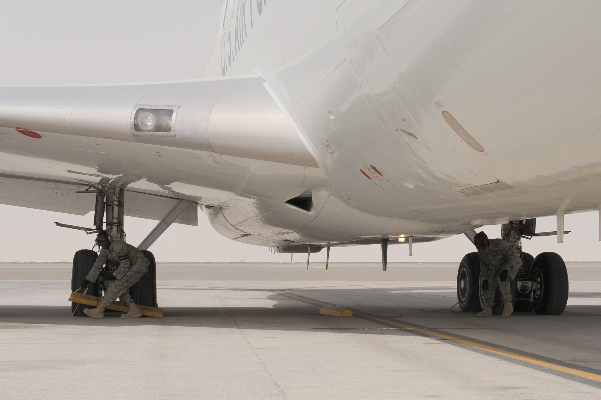 SOUTHWEST ASIA - Airman 1st Class Brett Catledge and Airman 1st Class Reshard Saladin, 380th Expeditionary Aircraft Maintenance Squadron, Sentry Aircraft Maintenance Unit, pull the chalks from an E-3 Sentry prior to its take-off, June 10 at an undisclosed location in Southwest Asia. The Sentry maintainers work around the clock performing maintenance, launching and recovering the aircraft, keeping it flying the tasking order every day. (U.S. Air Force photo by Senior Airman Brian J. Ellis) (Released)