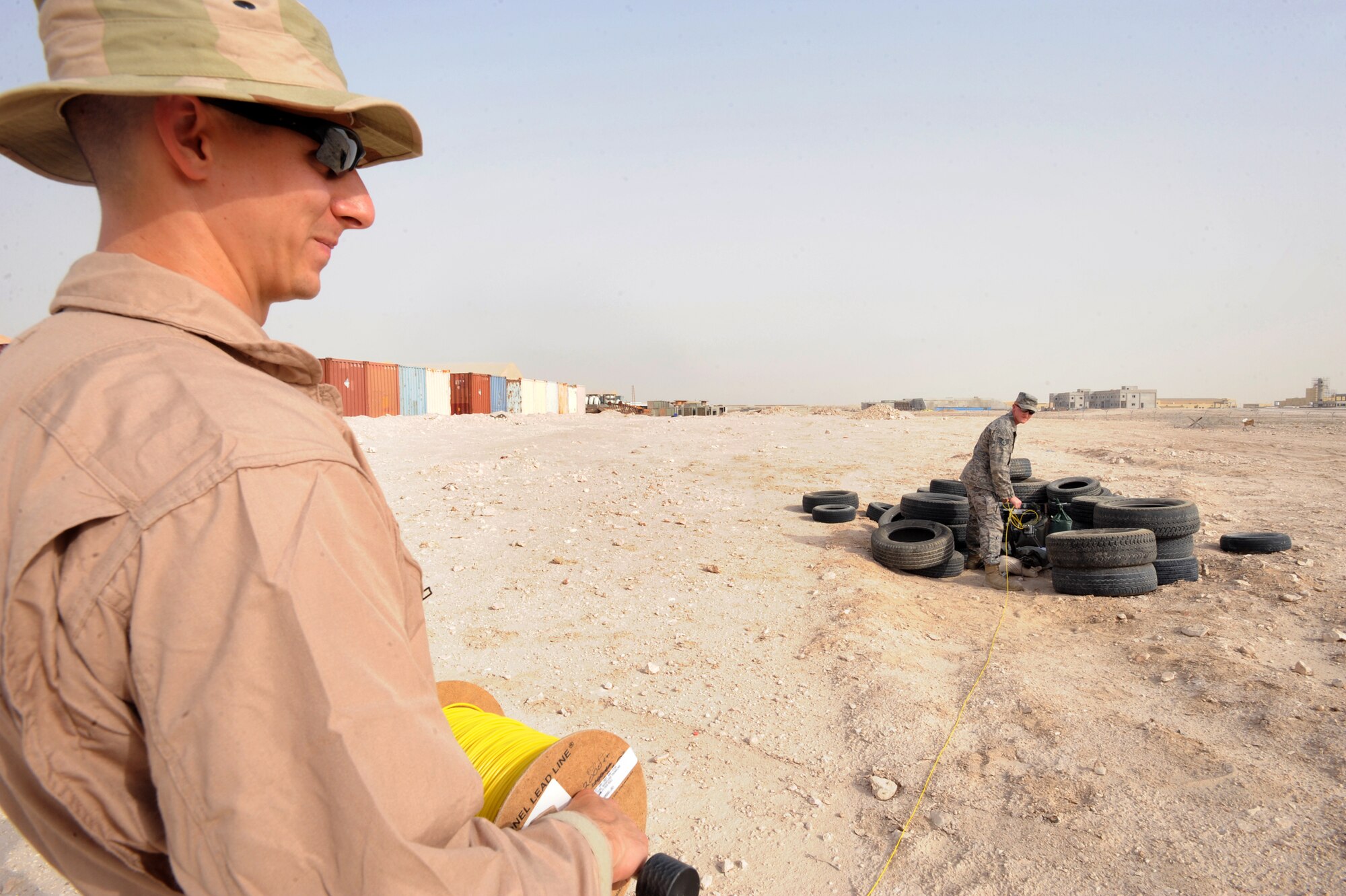 Senior Airman Michael Ault, reels out shock tube for the Percussion Actuated Neutralizer (PAN) as Sergeant George Schmalz, both explosive ordnance disposal personnel with the 379th Expeditionary Civil Engineer Squadron, sets the PAN in position for a training shot, June 12, 2009, in an undisclosed location in Southwest Asia.  The PAN is an alternate method used by EOD personnel to disarm explosives. Airman Ault is native to Austin, Texas, while Sergeant Schmalz hails from Enola, Penn. Both are deployed from Charleston Air Force Base, S.C., in support of Operations Iraqi and Enduring Freedom and Combine Joint Task Force - Horn of Africa.  (U.S. Air Force Photo by Staff Sgt. Joshua Garcia/released)