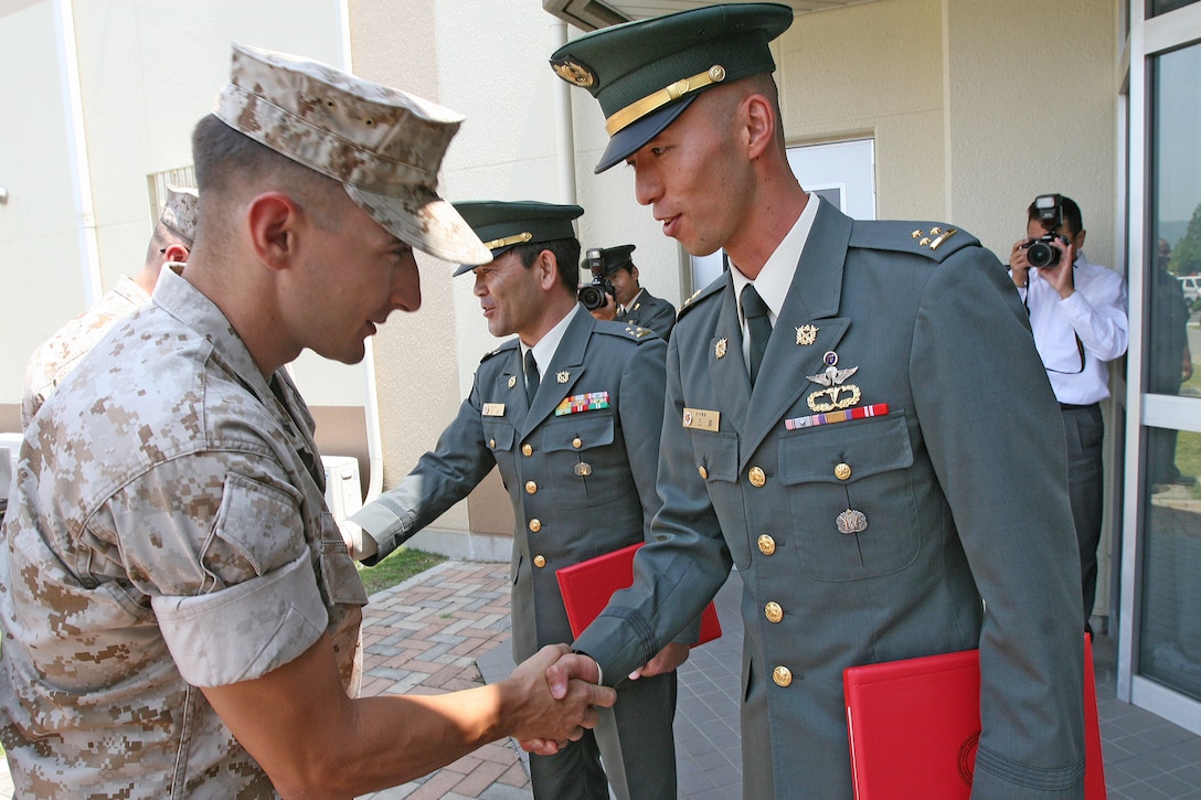 Marines congratulate Capt. Shigeru Miura, Japan Ground Defense Force 1st company commander, and Capt. Minoru Hanada, JGSDF liason for base cluster four, after recieving certificates of commendation at a ceremony held outside the Provost Marshal’s Office here June 17. Both gentlemen recieved their certificates for outstanding support during Active Shield Nine, and evaluation of the air station’s bilateral defense measures.