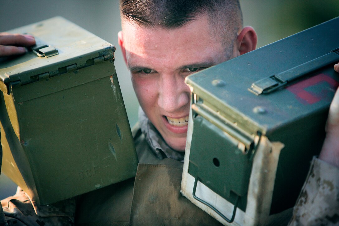 Lance Cpl. Donald F. Marshall, a Headquarters and Headquarters Squadron Super Physical Fitness Test competitor, struggles to hold two 30-lb. ammunition cans on his shoulders as he walks from the obstacle course near Ironworks Gym to the Penny Lake athletic fields here (a distance of nearly a mile) to then complete a Combat Fitness Test June 17. Marshall was competing for a chance to ride in the back seat of an F/A-18 fighter jet in an upcoming deployment.