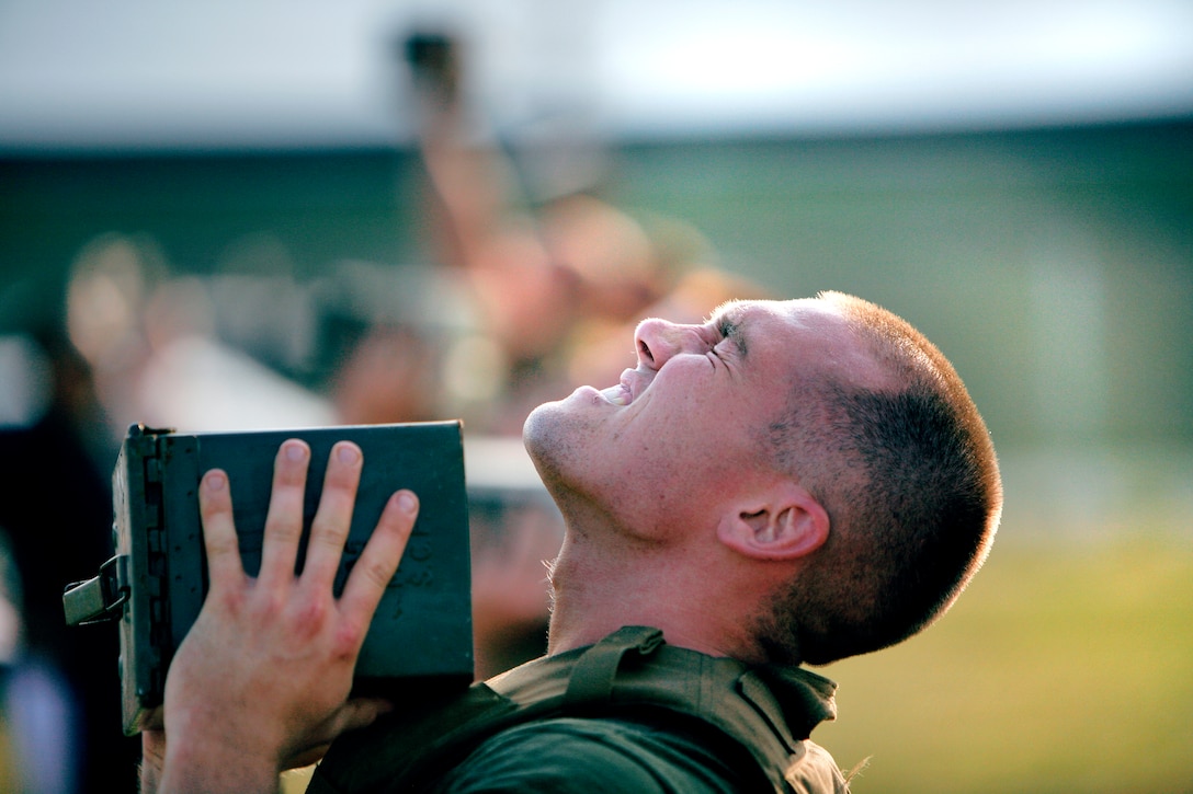 Lance Cpl. Richard P. Keller struggles to lift a 30-lb. ammunition can above his head during the Super Physical Fitness Test put on by Headquarters and Headquarters Squadron June 17. Keller and other competitors completed a PFT, Combat Fitness Test, a run through an obstacle course and other physical feats while wearing a flak jacket and combat utility uniform for a special chance to ride in the back seat of an F/A-18 fighter jet in an upcoming deployment.
