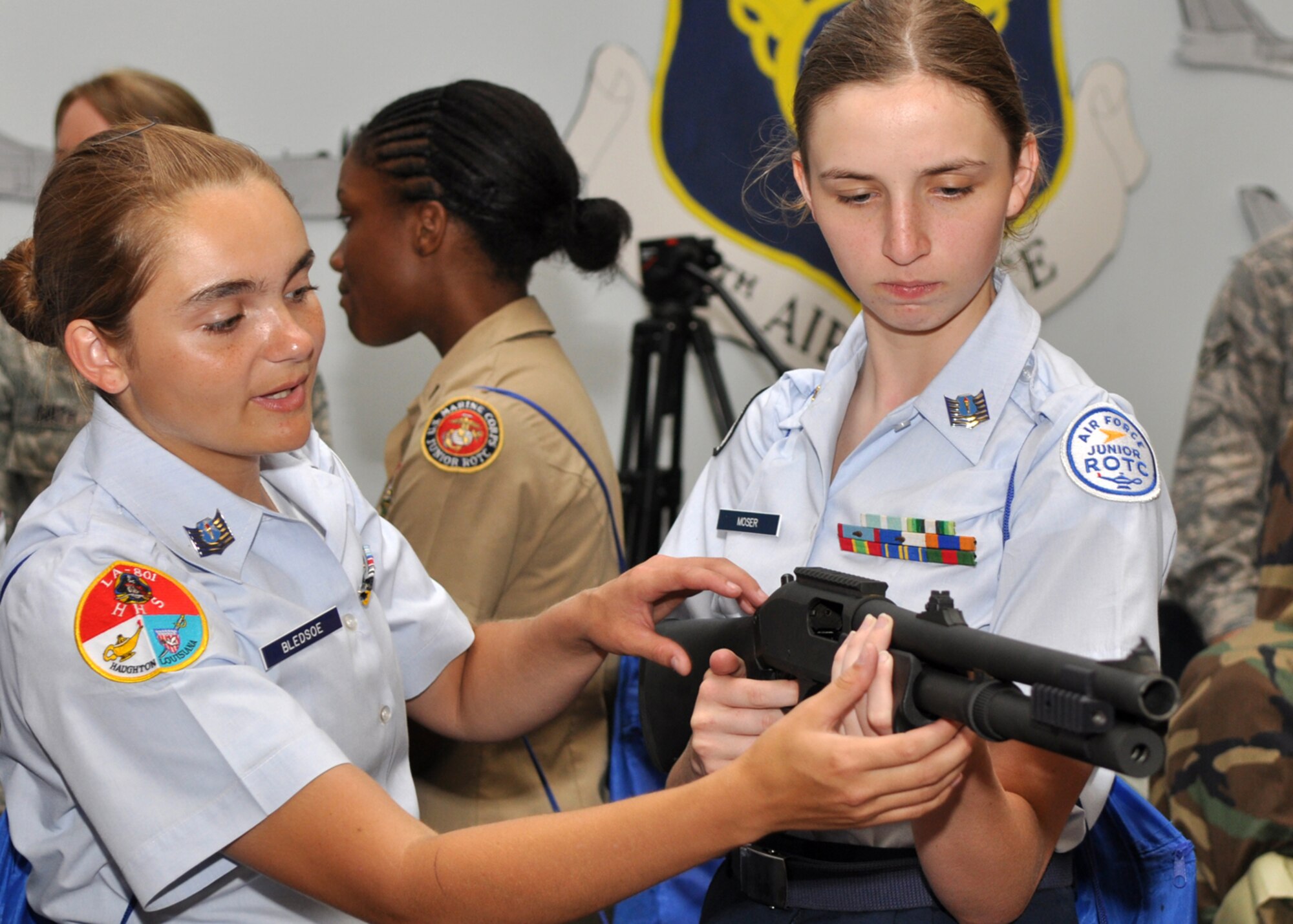 Air Force Junior Reserve Officers’ Training Corps Cadets Jessica Moser and Julliane Bledsoe familiarize themselves with a modified M870 12 gauge shotgun under the watchful eye of 2nd Security Forces Squadron member Tech. Sgt. David Parker, during a small arms briefing in Hoban Hall at Barksdale Air Force Base, La., June 18, 2009, during a “Summer Leadership School” for JROTC cadets. Barksdale AFB personnel broke out all manners of equipment for demonstrations and briefing for the cadets on the capabilities of the U.S. Air Force and Barksdale personnel. The eight-day school is designed to encourage the cadet’s leadership skills. Each cadet is chosen by for the school by unit officials after the cadet passes certain criteria. The cadet must also maintain a “C” average in school. Cadets who participated came from high school units in Louisiana, Mississippi, Tennessee, Kansas, Oklahoma and Texas. Most were Air Force JROTC units, but there was also one Marine JROTC unit from Alexandria Senior High School in attendance. The JROTC motto is “Building Citizenship and Character in the Youth of America.” (U.S. Air Force photo/Tech. Sgt. Jeff Walston)