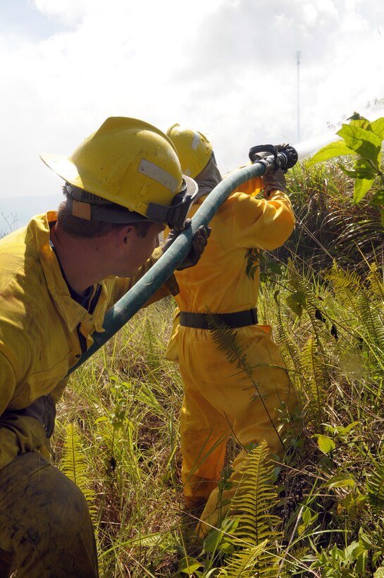 ANDERSEN AIR FORCE BASE, Guam - Staff Sgt. William Pease and Eric Masur, 36th Civil Engineer Squadron firefighters, work their way through the dense brush to more effectively target the fire working its way up the ridge June 17.  Firefighters worked from 1 to 6 p.m. to contain and extinguish a wild fire that burned approximately 50 acres on Mt. Santa Rosa.  The fire threatened two Department of Defense sites valued at $30 million, a commercial site valued at $1.4 million and 27 houses.  A combined effort by the Guam Fire Department, Andersen AFB Fire Department, Navy Helicopter Sea Combat Squadron 25 aerial support, Navy Fire Department, 36th Civil Engineer and the 554th RED HORSE Squadron totaling 68 people and 13 support vehicles contained the fire. (U.S. Air Force photo by Tech. Sgt. Michael Boquette)
