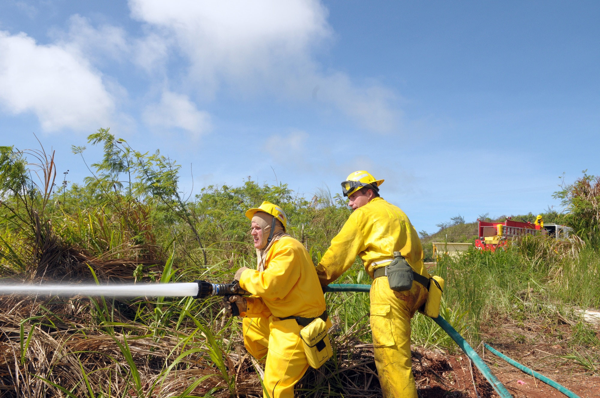 ANDERSEN AIR FORCE BASE, Guam - Staff Sgt. William Pease and Eric Masur, 36th Civil Engineer Squadron firefighters, work as a team to ensure best application of the water in extinguishing the encroaching flames June 17.  Firefighters worked from 1 to 6 p.m. to contain and extinguish a wild fire that burned approximately 50 acres on Mt. Santa Rosa.   (U.S. Air Force photo by Tech. Sgt. Michael Boquette)