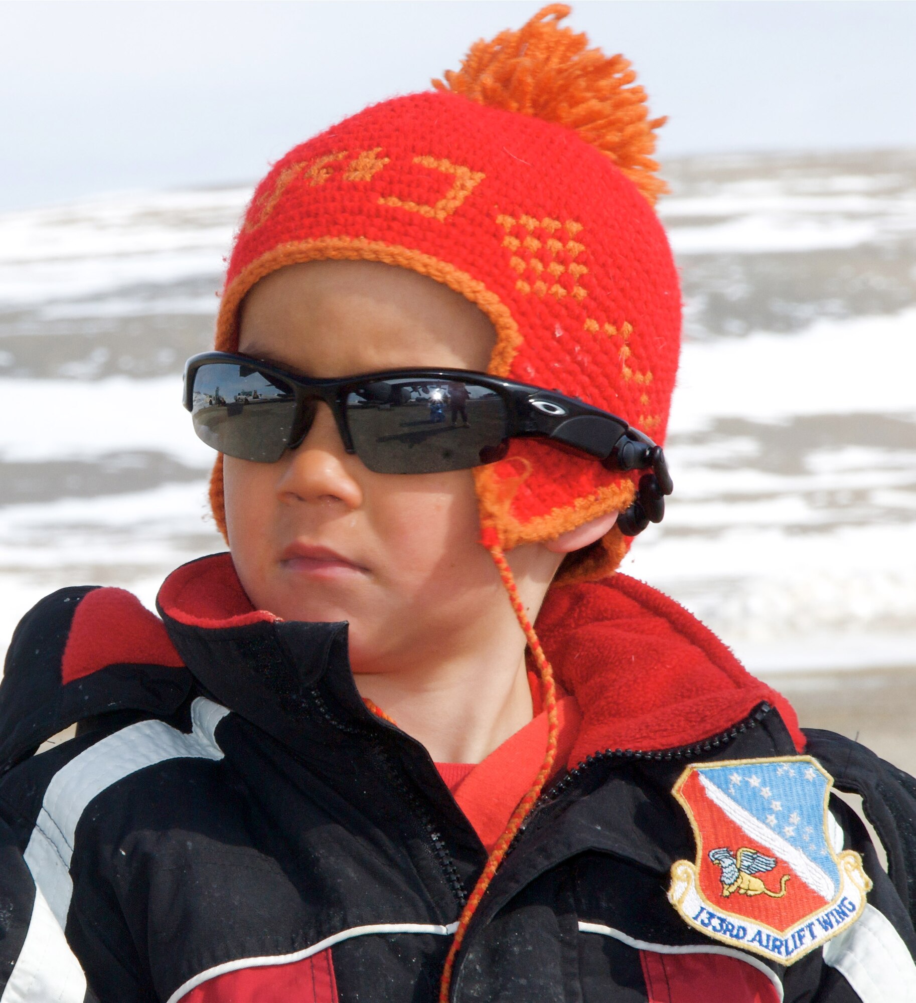 A local Inuit boy watches intently, wearing a new 133rd Airlift Wing patch on his jacket given to him by the Mission Commander Lieutenant Colonel Andrew Burda 109th Airlift Squadron as a Minnesota Air National Guard C-130 Hercules cargo aircraft unloads "Moon-1 in Resolute, Canada. The C-130 is being used to transport the Haughton-Mars Project Moon-1 Humvee Rover 28 May 2009.  HMP supports an exploration program aimed at developing new technologies, strategies, human's factors experience, and field-based operational know-how key to planning the future exploration of the Moon and Mars. The "Moon-1" can be seen with traditional tires for transportation while the tracks will be loaded separately which are needed for the adverse conditions the vehicle must through.
U.S. Air Force Photo by Tech Sgt Erik Gudmundson (Released)
