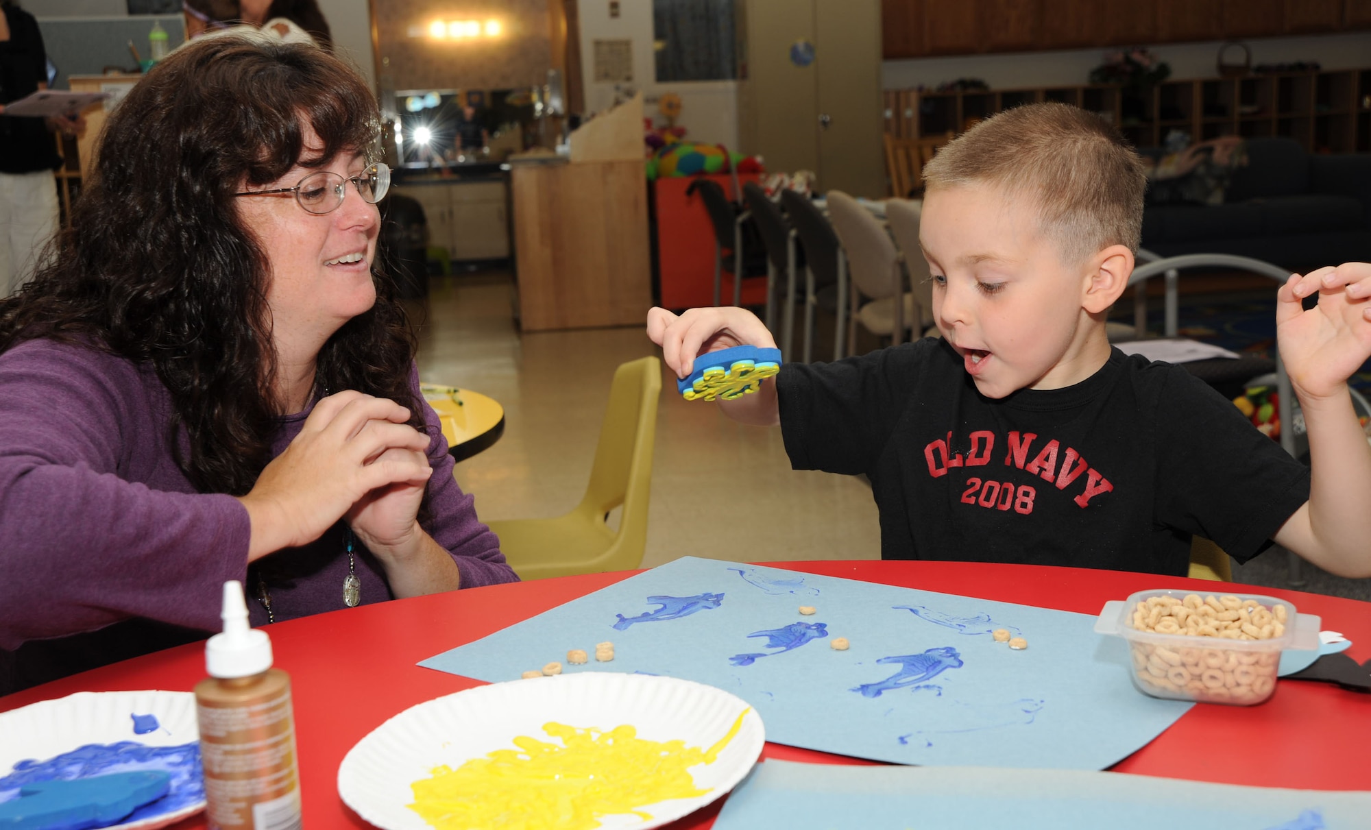 MCCONNELL AIR FORCE BASE, Kan. -- Deborah Whitfield, Parents as Teachers representative, observes Michael Hisey, 4, son of Senior Airman Tim Hisey, 22nd Civil Engineer Squadron, make a craft during the Cookie Bookie Club story time at Play Group, June 10. The event happens once a month during the school year. The Cookie Bookie Club story time started in 2002 and gives children a chance to read books and create crafts related to the story. They also decorate and eat cookies. (Photo by Senior Airman Roy Lynch) 
