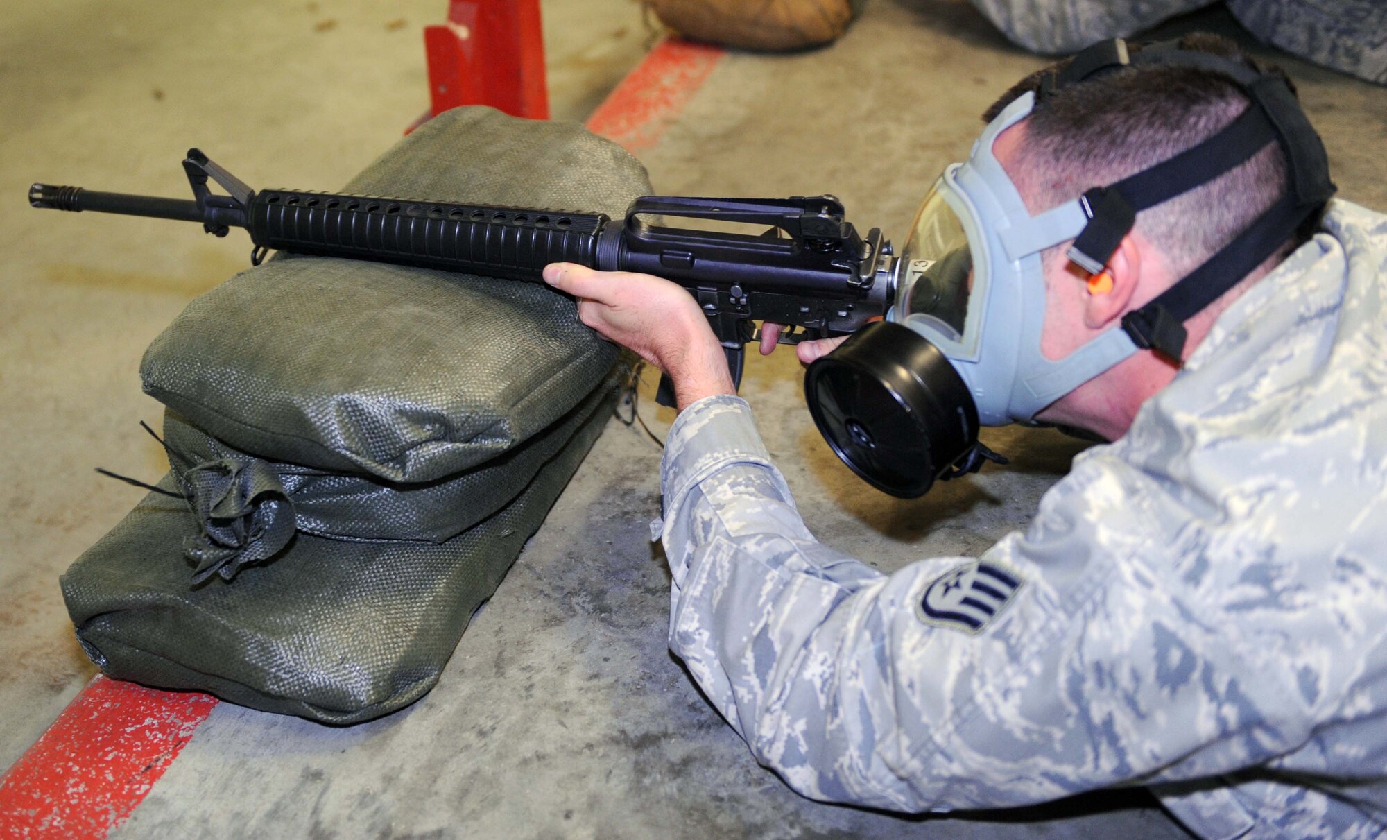 Staff Sgt. Christopher Payne, 4th Aircraft Maintenance Squadron armament technician, fires an M-16 carbine at the Combat Arms Training and Maintenance facility on Seymour Johnson Air Force Base, N.C., June 16, 2009. Firing with a gas mask is just one portion of M-16 qualification training. (U.S. Air Force photo by Airman 1st Class Gino Reyes)