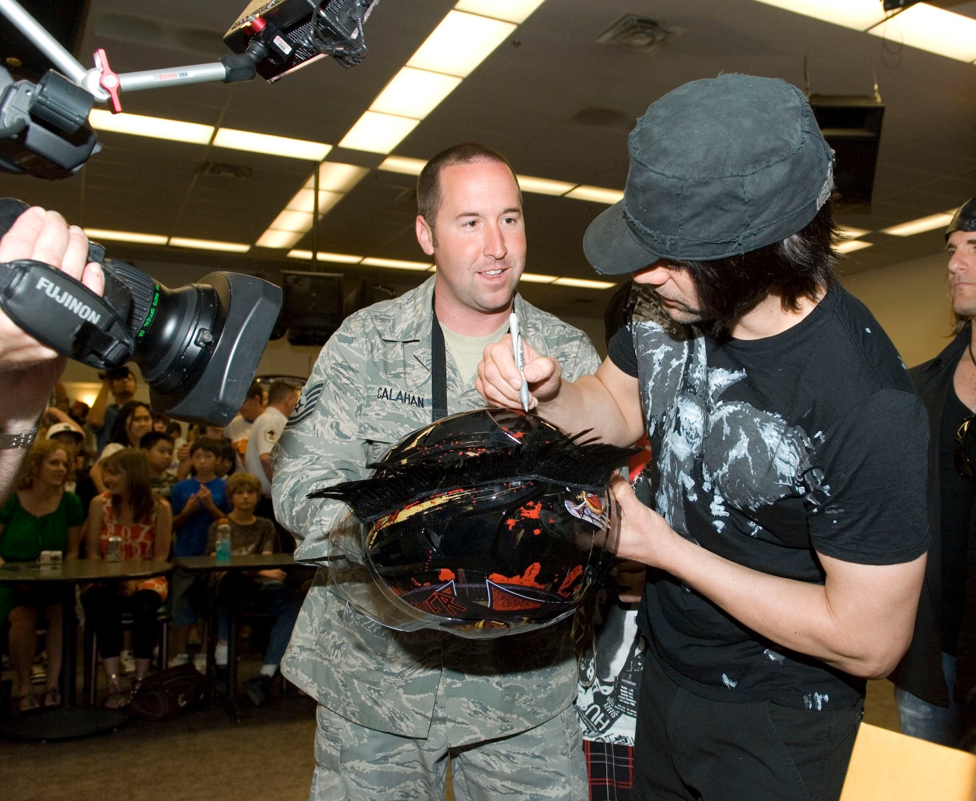 Criss Angel, star of the tevelesion show Mindfreak, autographs a motorcycle helmet for Tech. Sgt. Chad Callahan, F-22 Raptor Combine Test Force crew chief, during his visit. Sergeant Callahan said he is a big Criss Angel fan and was excited to meet him and get his autograph. More than 200 fans attended the autograph signing. (Air Force photo/Mike Yncera)