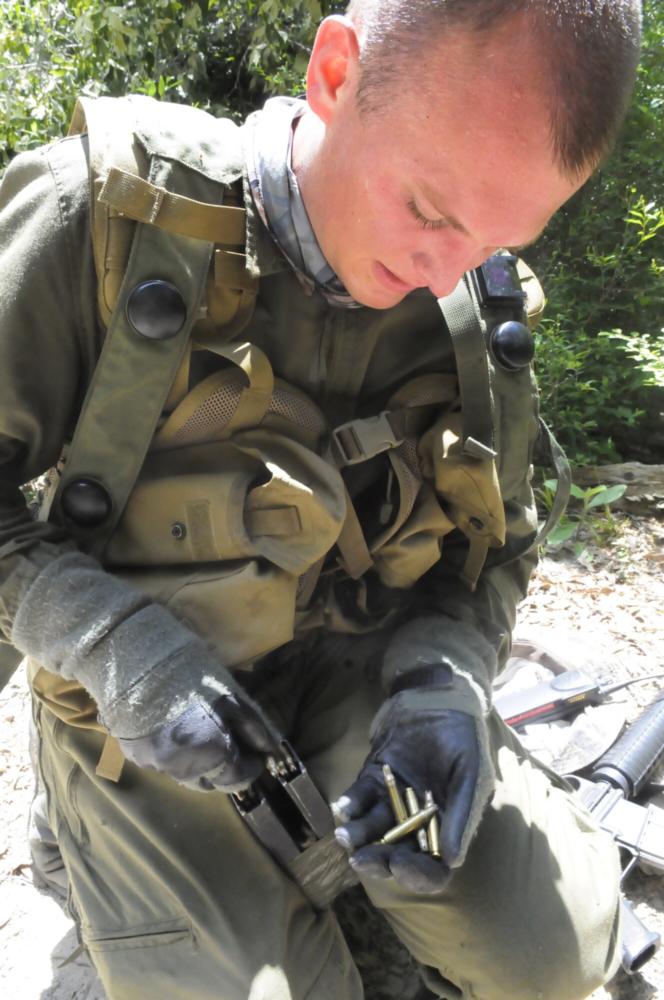 Cadet Aric Benkoski reloads his M-16 in the woods at Warrior Air Base June 12. The cadets acted as aggressors while taking part in 5th CCG Gator Gully training. U. S. Air Force photo by Sue Sapp