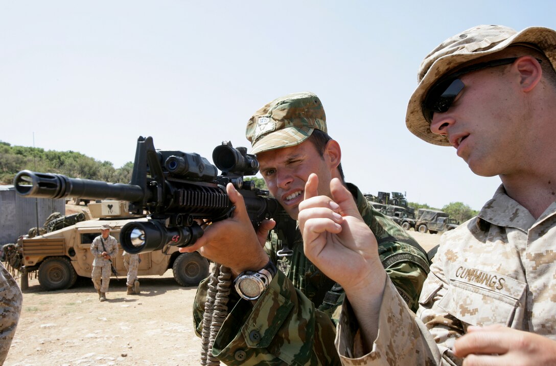 U.S. Marine 1st Lt. Jeffrey A. Cummings, right, describes the rifle combat optic of his M4 carbine to Greek Marine 2nd Lt. Nikos Stamadiou, a platoon leader for the 32nd Brigade of Marines, at Melissatika training area outside Volos, Greece, June 11, 2009. Cummings is the officer in charge of Combined Anti-Armor Team, Weapons Company, Battalion Landing Team, 3rd Battalion, 2nd Marine Regiment, 22nd Marine Expeditionary Unit.