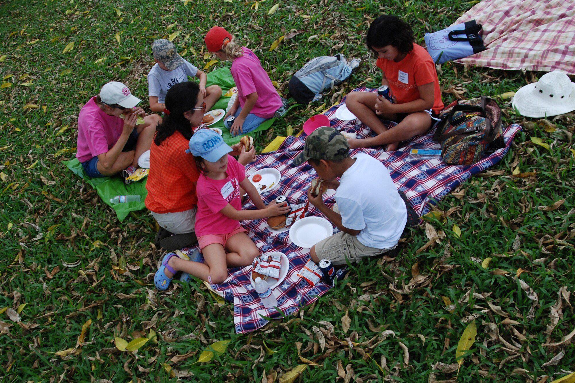 KANEOHE, Hawaii -- Lucy Graham and family, as well as Kara Kuder and family, sit and eat hamburgers and hotdogs picnic style during the 10th Annual Keiki Fishing Tournament June 10 at the Ho'omaluhia Botanical Gardens. More than 170 children and their families were treated to lunch and a Polynesian Culture Center demonstration before the fishing tournament began. The keiki caught a record-setting 449 fish at the tenth annual tournament. (U.S. Air Force photo/Staff Sgt. Mike Meares)