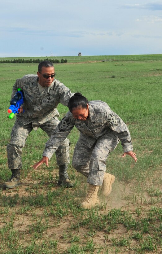 BUCKLEY AIR FORCE BASE, Colo. -- Col. Vincent Jefferson, 460th Mission Support Group commander, attempts to hold up Chief Master Sgt. Arleen Heath, 460th Space Wing Command Chief, after she spun around a bat as part of the obstacle course at the Combat Dining-in May 29 at Camp Rattlesnake here. More than 100 people showed up for the event. (U.S. Air Force photo by Senior Airman Alex Gochnour)