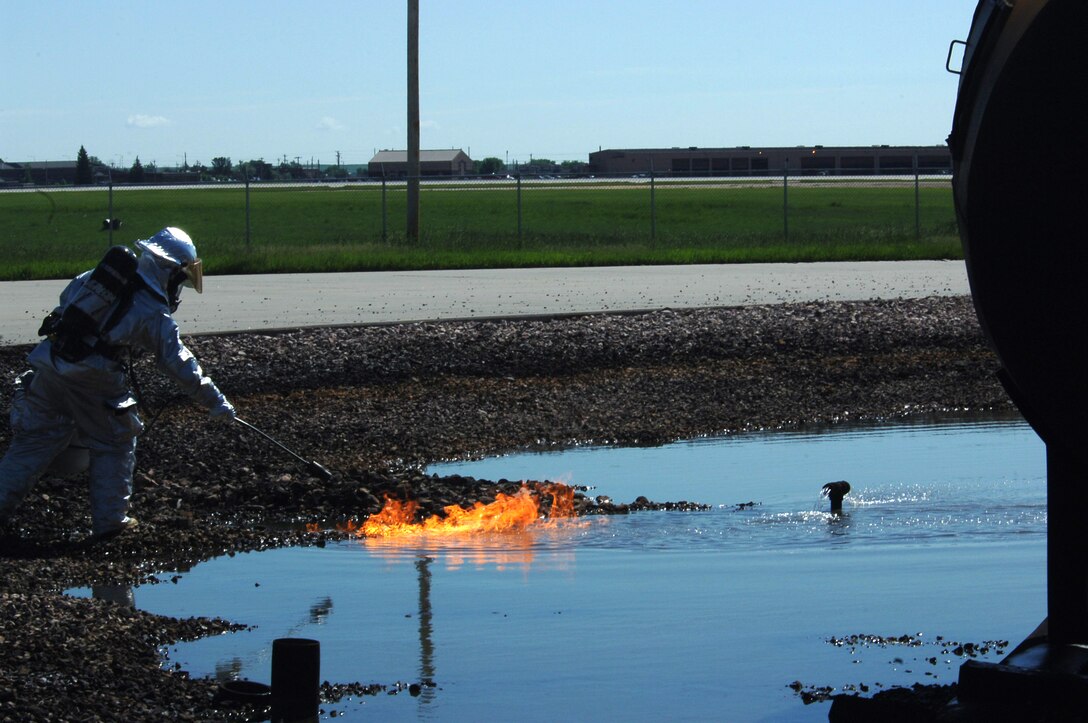 Senior Airman Ryan Logan, 28th Civil Engineer Squadron firefighter, ignites fuel, starting a pit fire here, June 19.  Ellsworth firefighters use pit fires to train new Airmen and Department of Defense civilian firefighters.  Pit fires are also used as refresher training for all 28th Bomb Wing firefighters. (U.S. Air Force photo/Senior Airman Anthony Sanchelli)